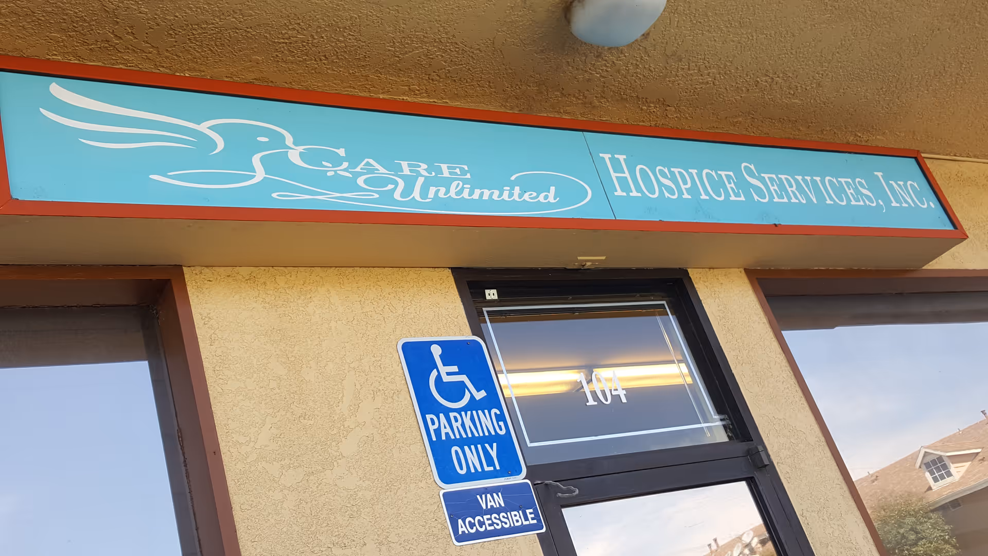 Exterior storefront signage for Care Unlimited Hospice Services, Inc., with handicap parking sign.