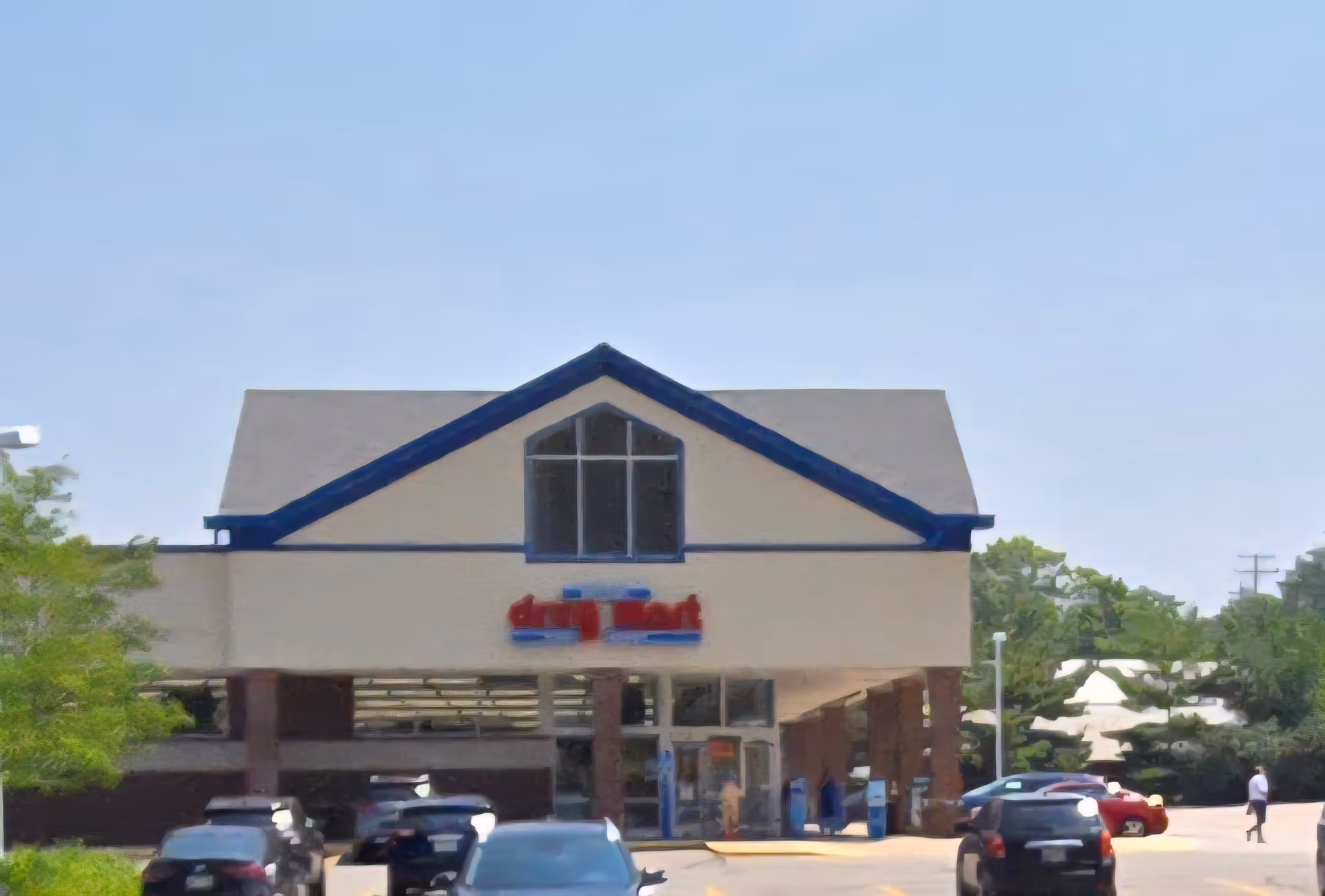 Discount Drug Mart storefront with a parking lot and cars under a clear sky.