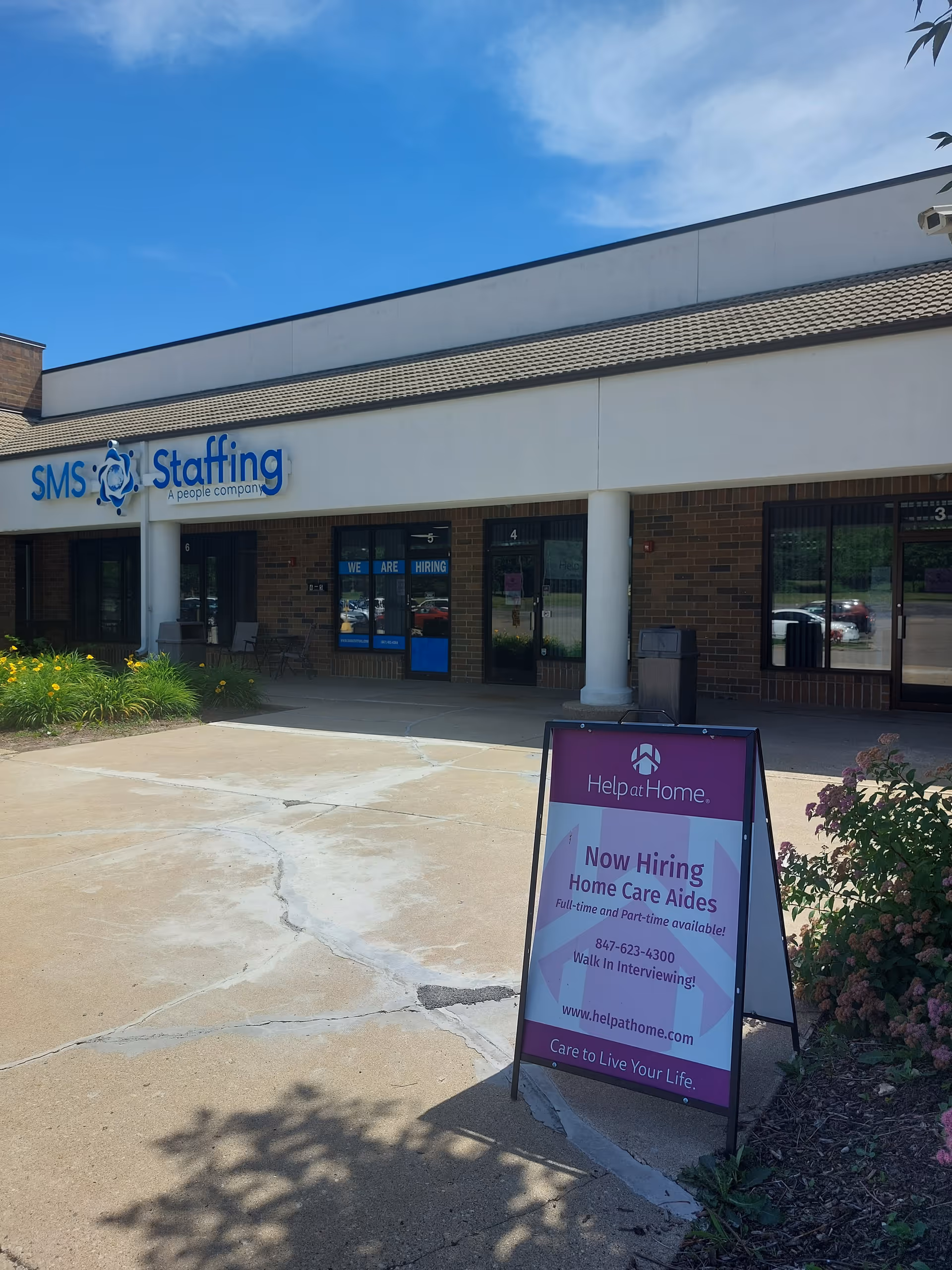 Exterior of Help at Home storefront with a Now Hiring sign.