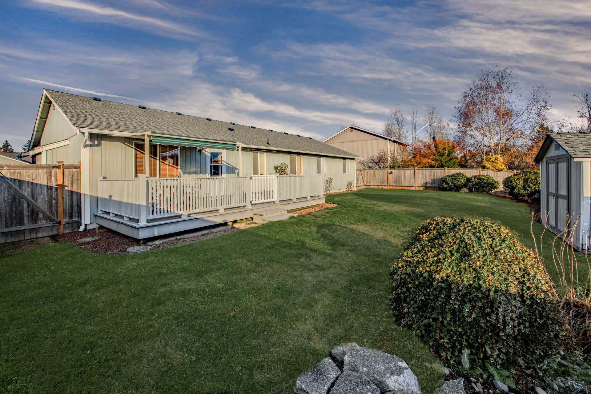 Exterior view of a single-story facility with a raised deck, green lawn, and fenced yard.