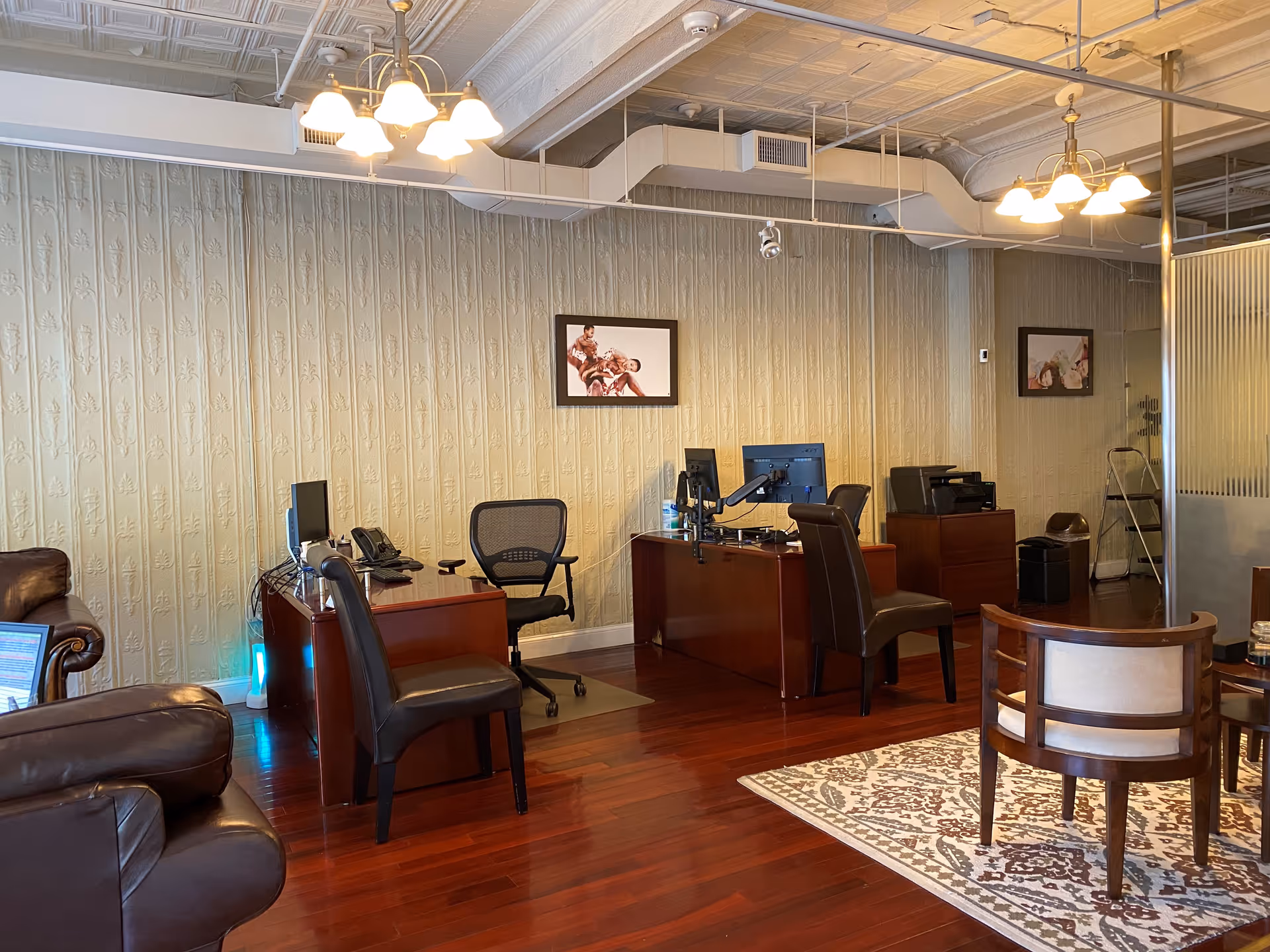 Office workspace with desks, computers, and seating in a warmly lit interior.