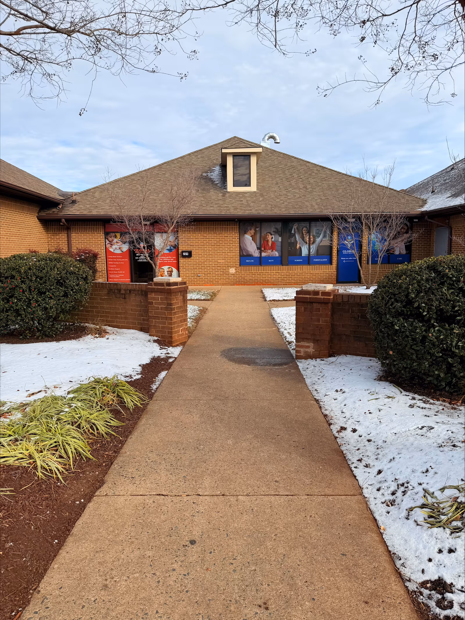 Exterior view of a brick senior facility with a walkway to the entrance.