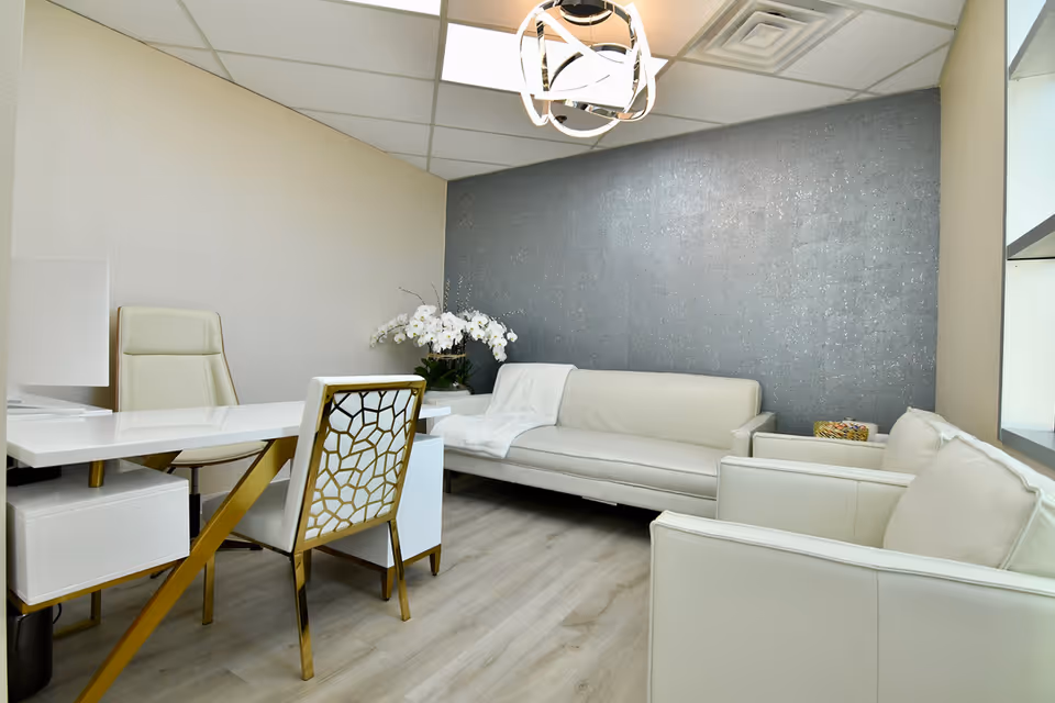 Modern white lounge area with sofas, a desk, and a geometric-patterned chair.