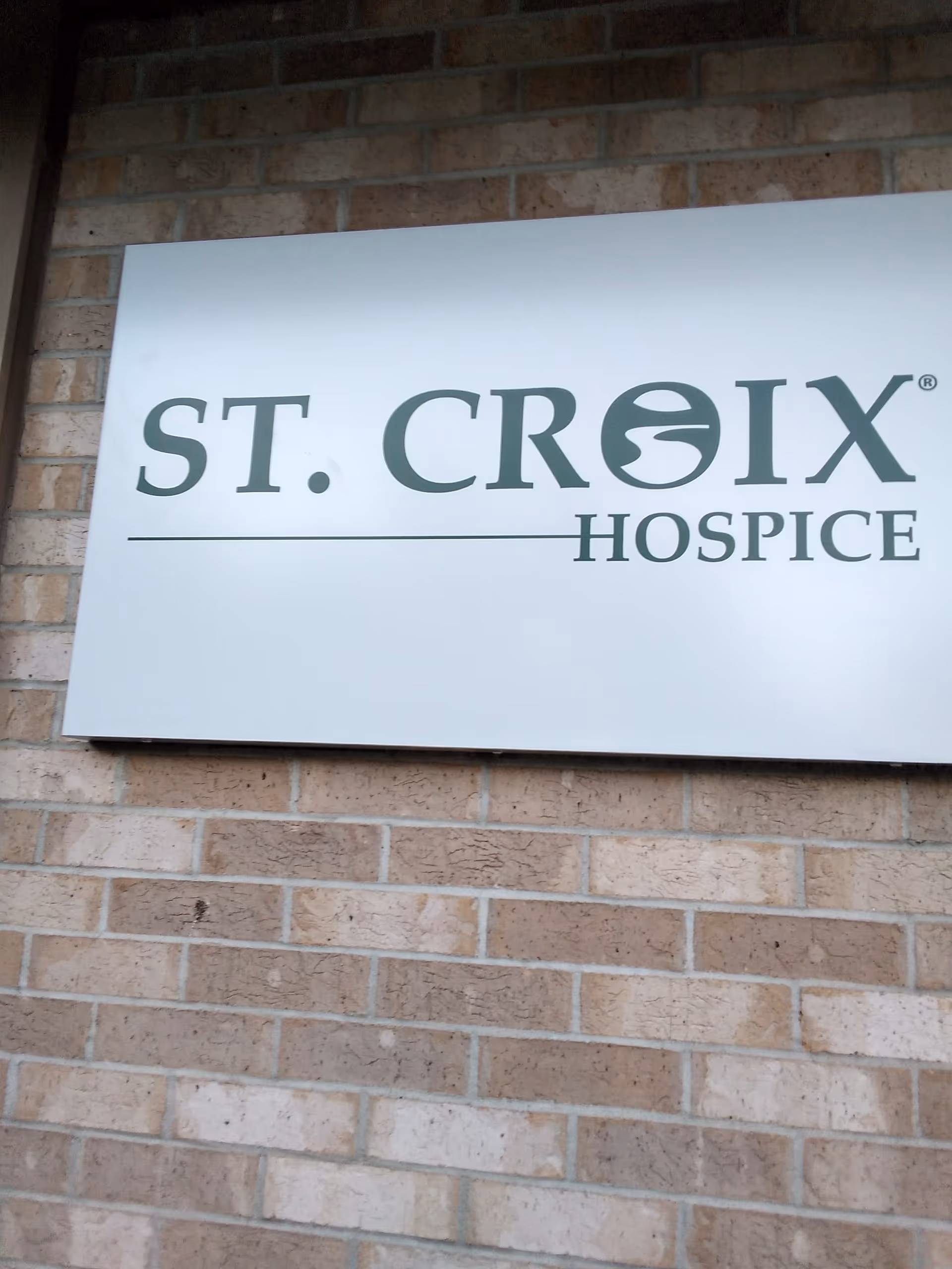 A white sign reading 'ST. CROIX HOSPICE' mounted on a brick exterior wall.