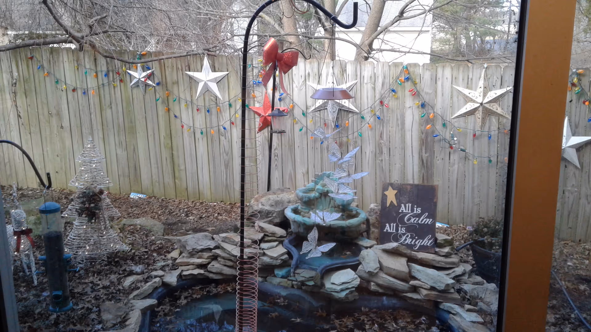 Backyard outdoor area with a rock fountain, string lights, stars, and garden ornaments.