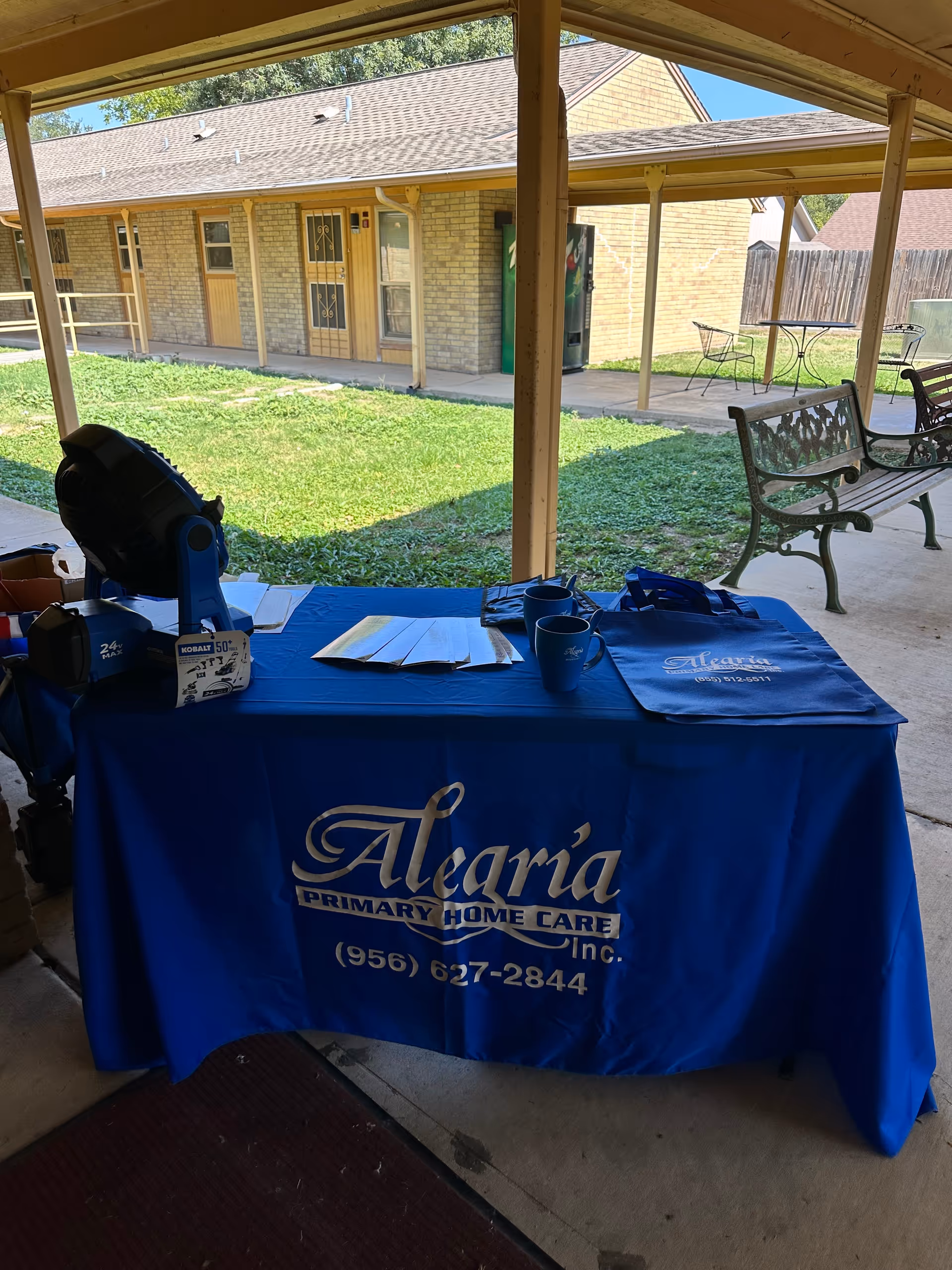 Blue Alegria Primary Home Care table on a covered patio with chairs and building behind