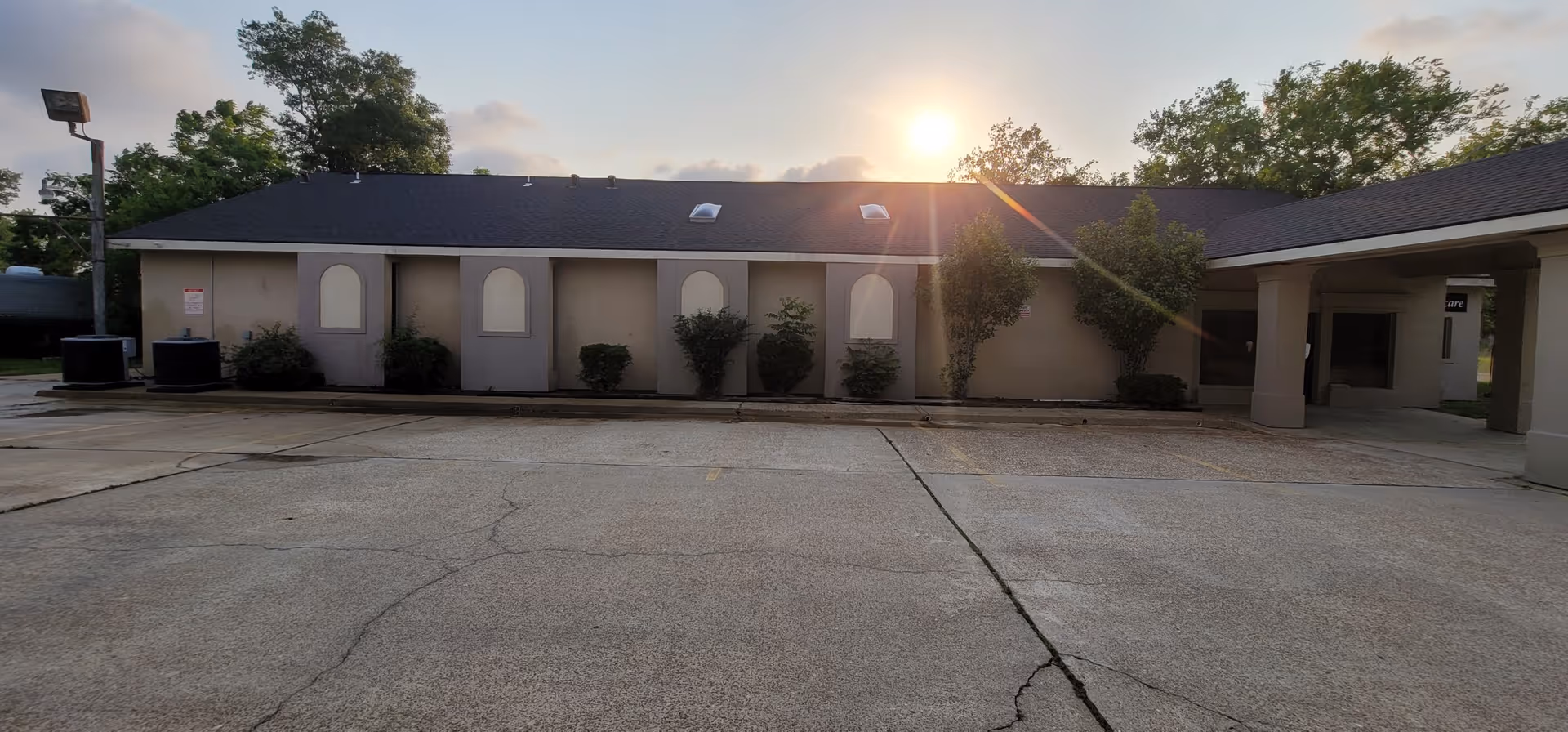 Exterior view of a senior living facility with arched windows and a covered entrance.