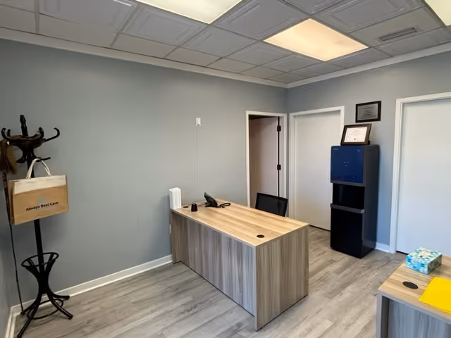 Reception desk in a gray-walled office with a coat rack and doorway.