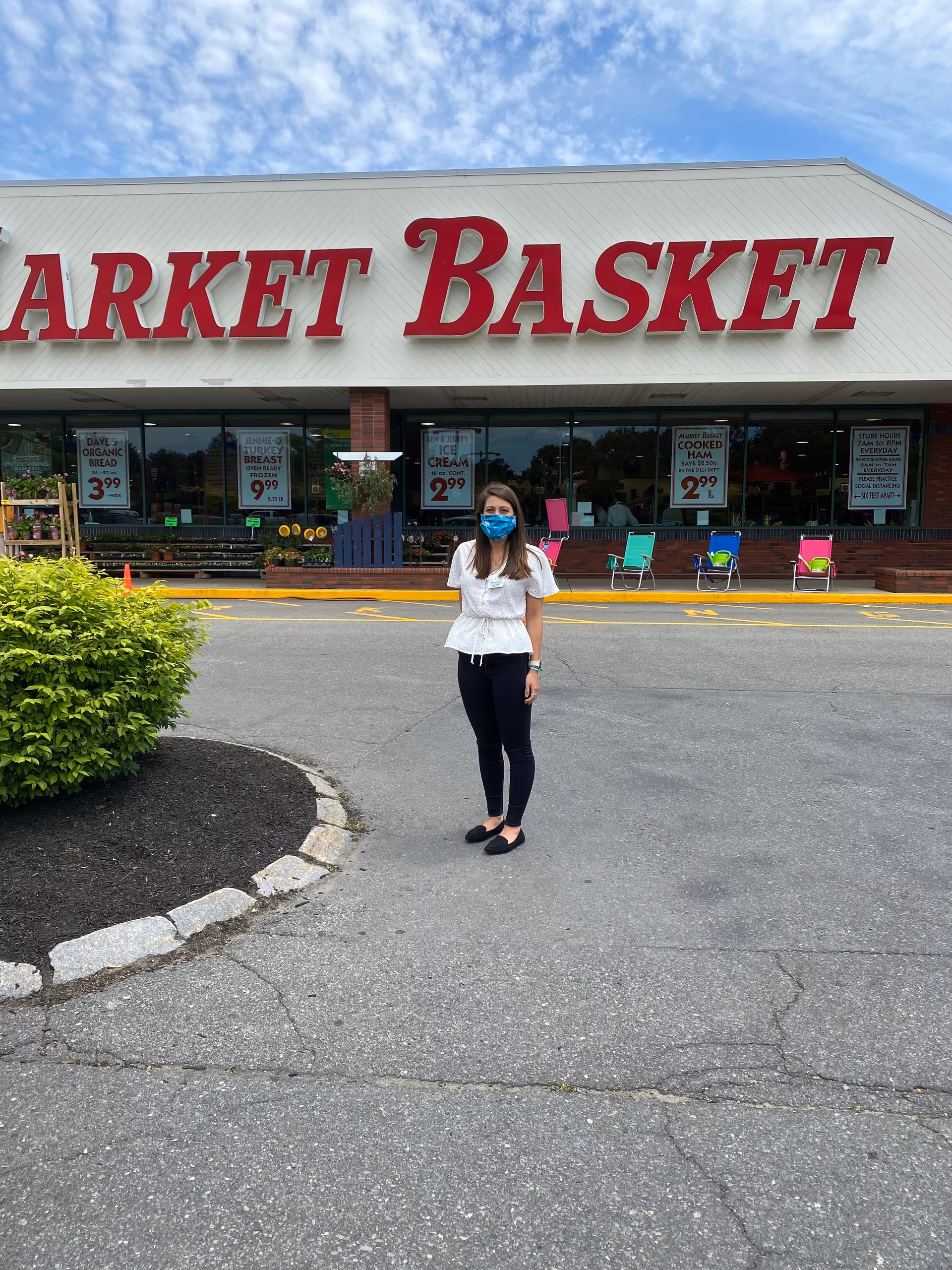 A person wearing a blue mask stands outside a Market Basket storefront.