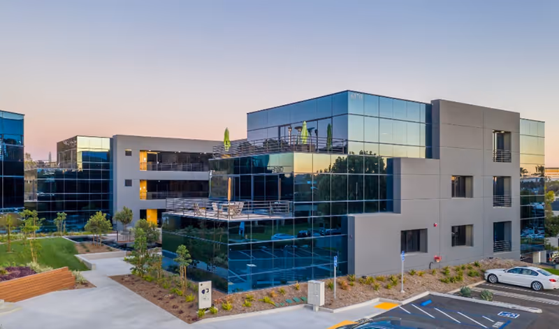 Pacific Point Health Care Services building with a glass facade, balconies, and surrounding parking.