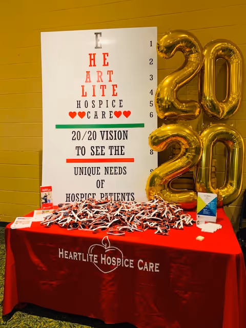 Indoor display table with Heartlite Hospice Alabama banner and gold 2020 balloons.