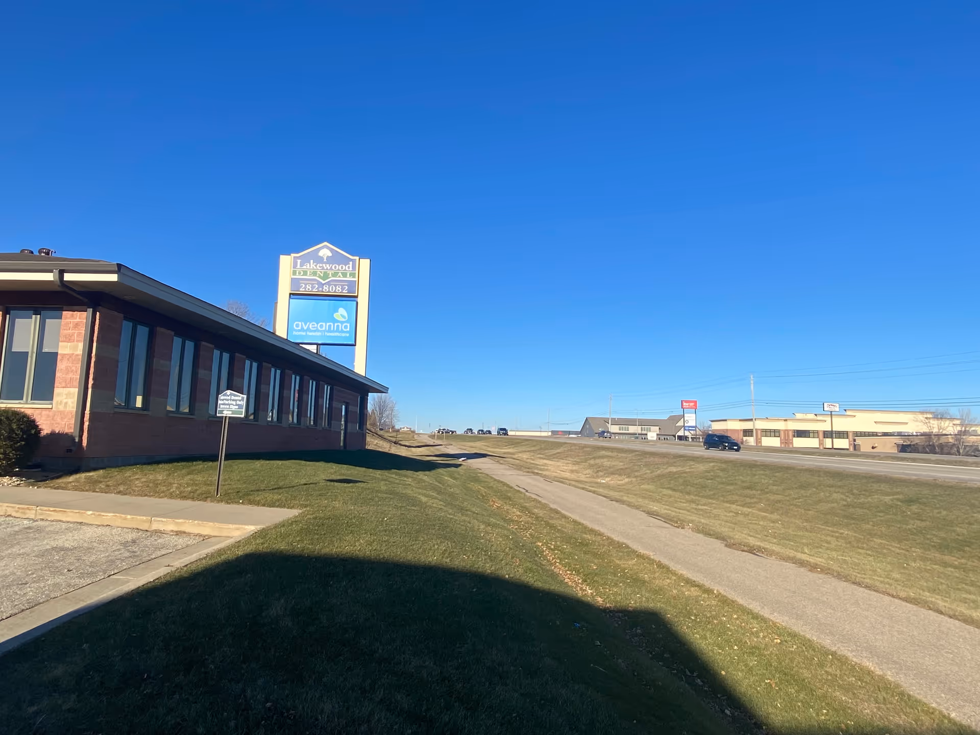 Exterior view of Aveanna Home Health building with sign, blue sky, and driveway.