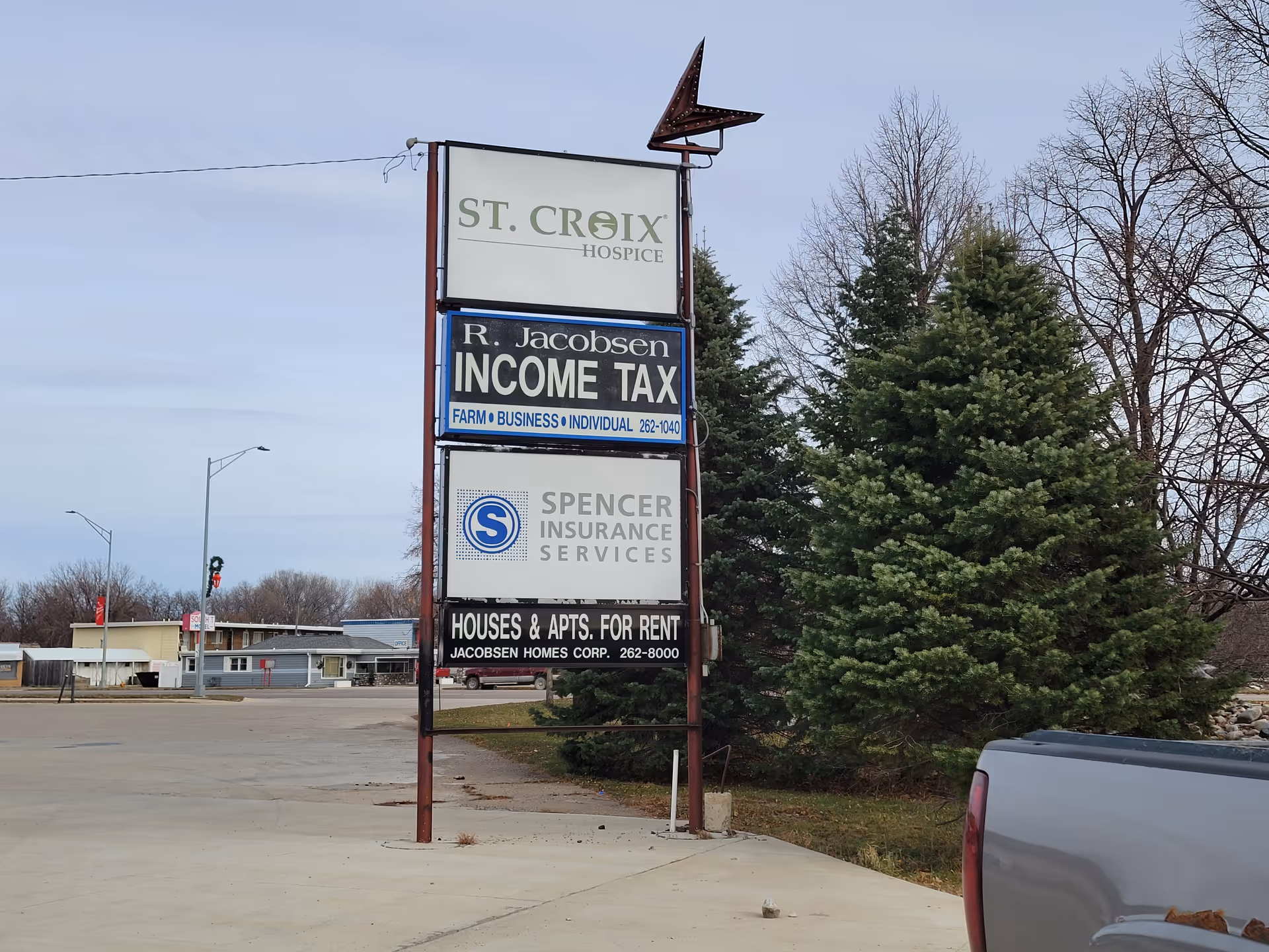 Tall multi-panel sign for St. Croix Hospice beside trees along a street