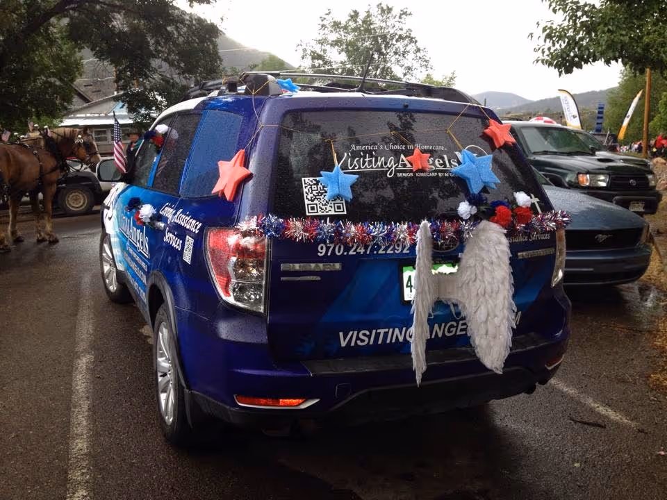 Blue Visiting Angels vehicle decorated with stars on a street parade.