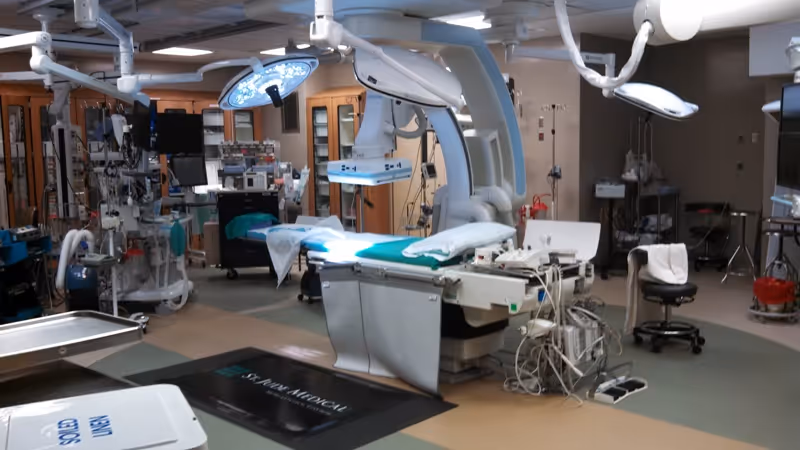 An advanced operating room with surgical table, overhead lights, and medical equipment.