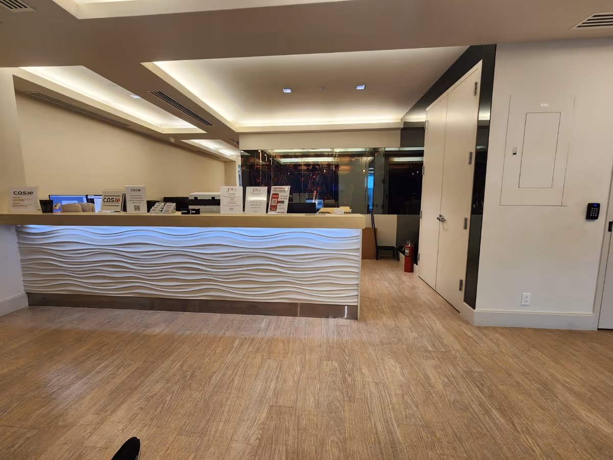 Modern lobby reception desk with a white, wavy front in a facility interior.