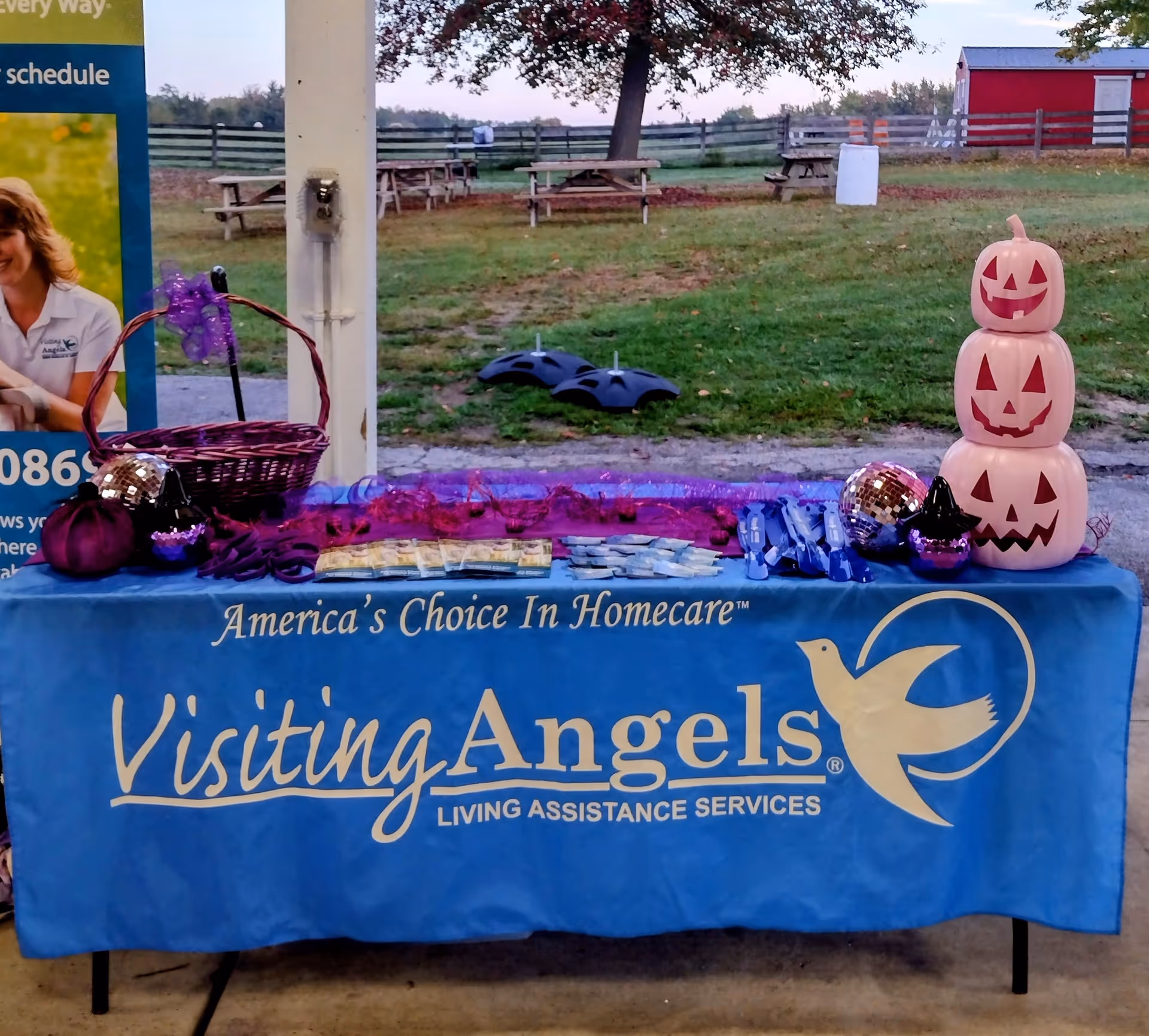 Outdoor promotional table for Visiting Angels with pumpkins and a blue banner