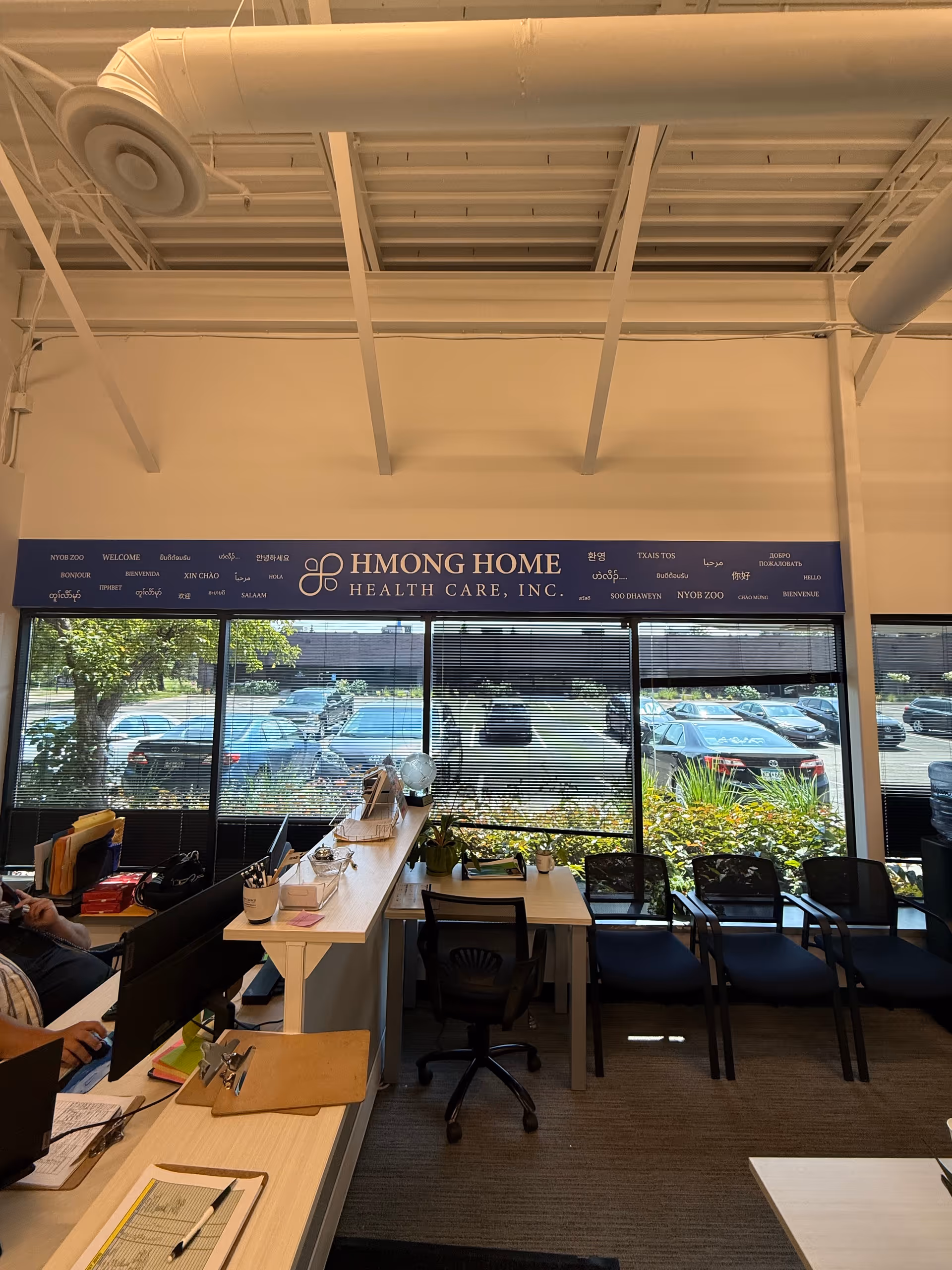 Interior reception area with desks, chairs, and a visible Hmong Home Health Care sign