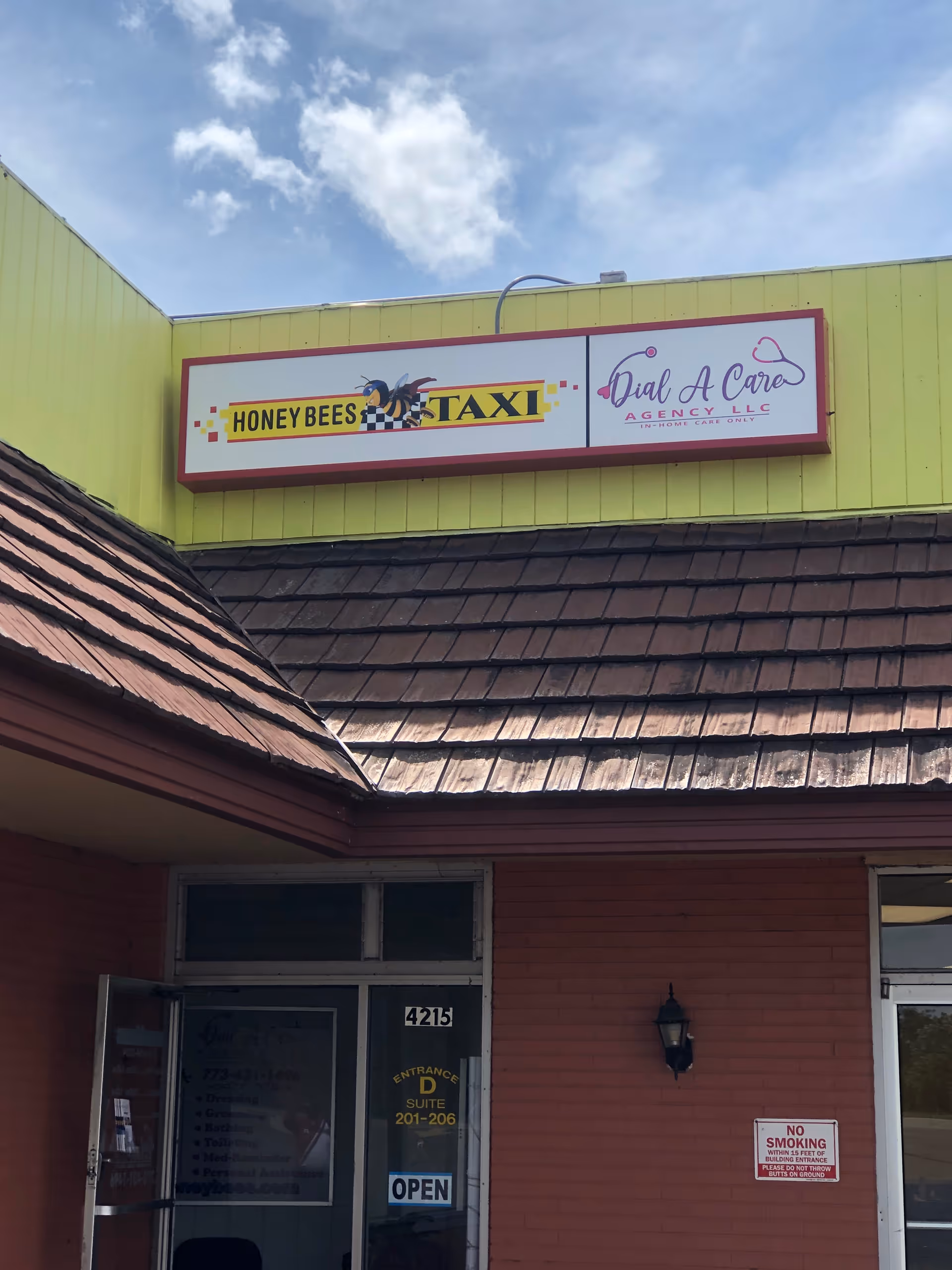 Yellow building exterior with Dial A Care Agency LLC and Honey Bees Taxi signs above entrance.