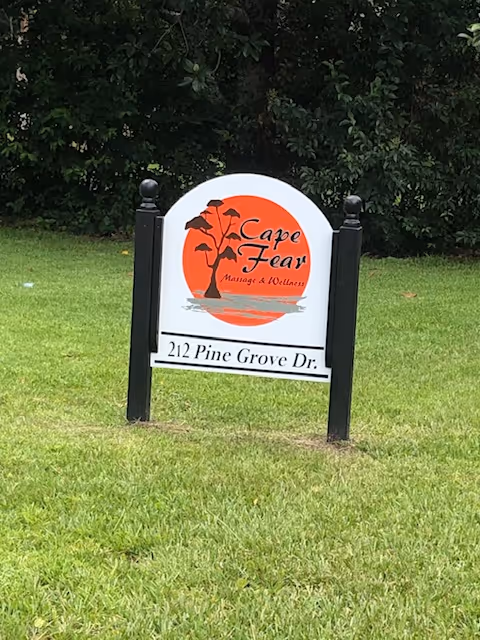 White arched sign on a grassy lawn with Cape Fear Massage & Wellness
