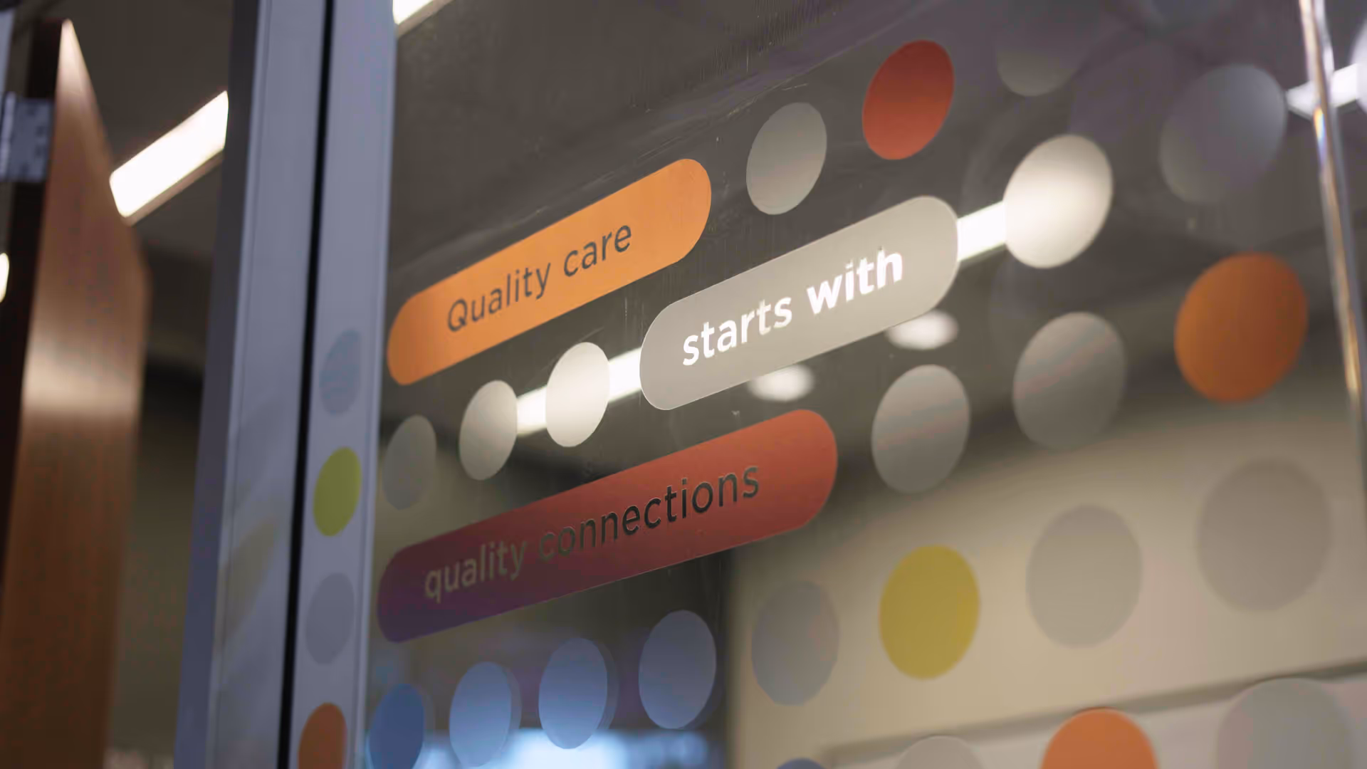 Interior glass panel with multicolored dots and phrases Quality care starts with quality connections.