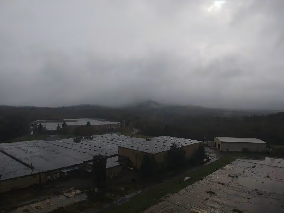 Overcast view of a senior living facility with flat-roofed buildings and distant hills.
