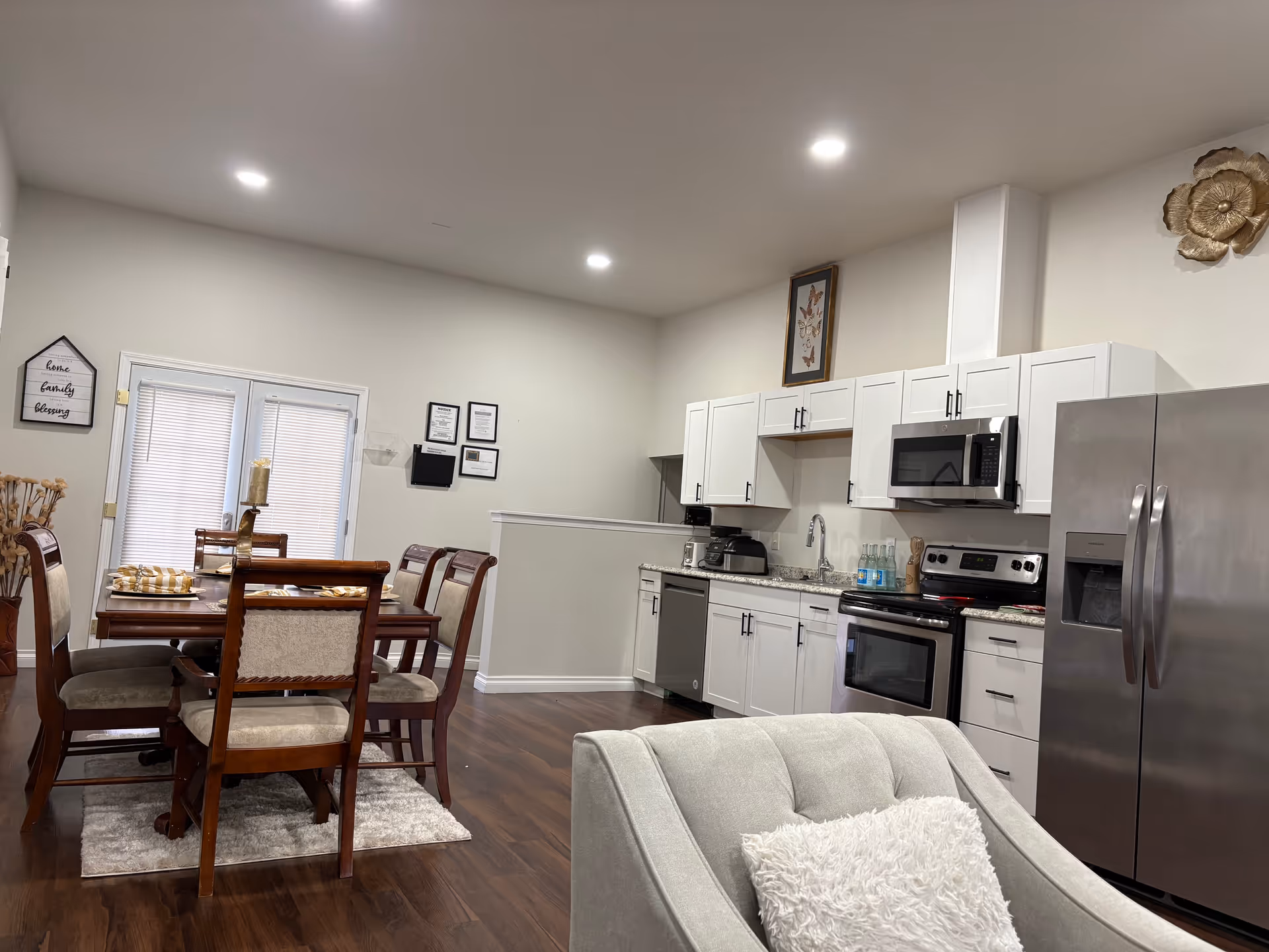 Open-concept kitchen and dining area in a senior living home with a gray chair.