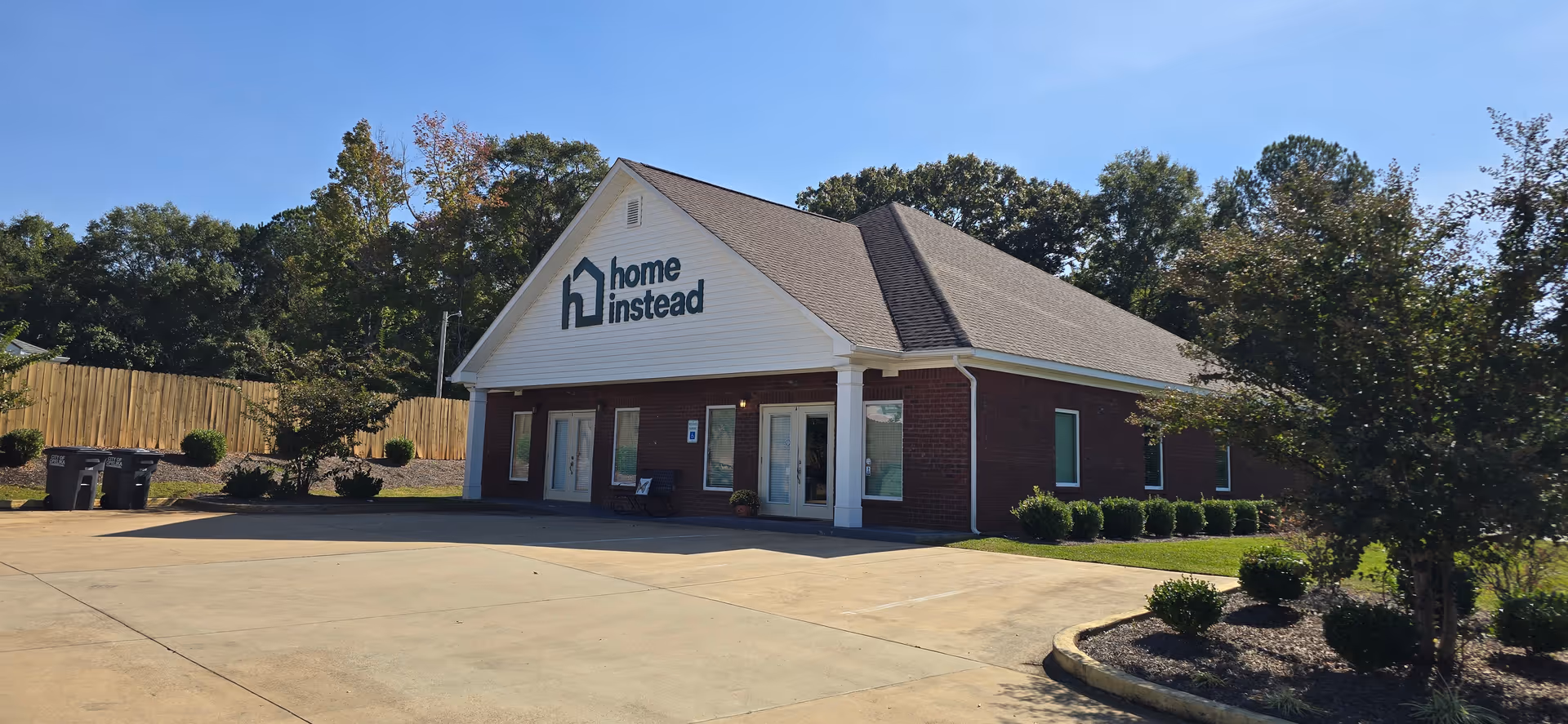Exterior front view of a Home Instead building with brick walls and landscaped entrance.