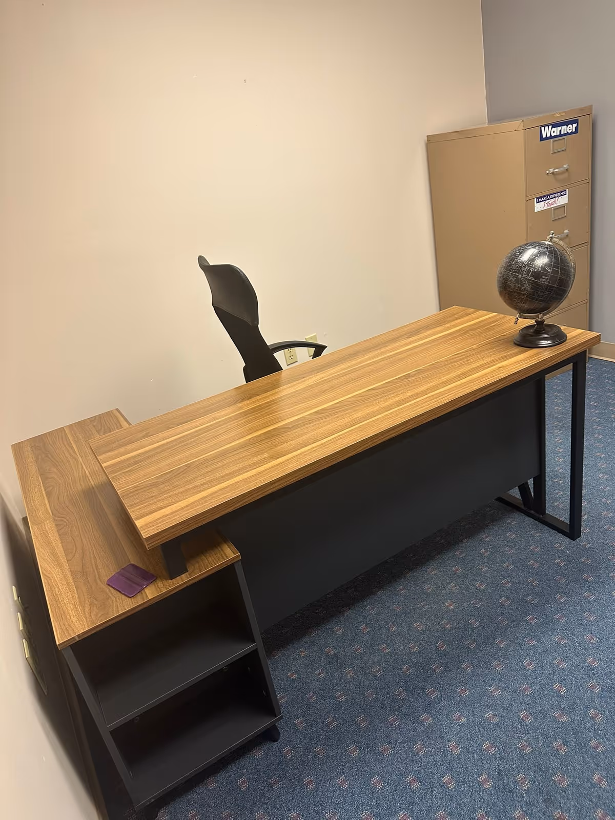 Wooden office desk with chair, globe, and safe in a small interior reception area.