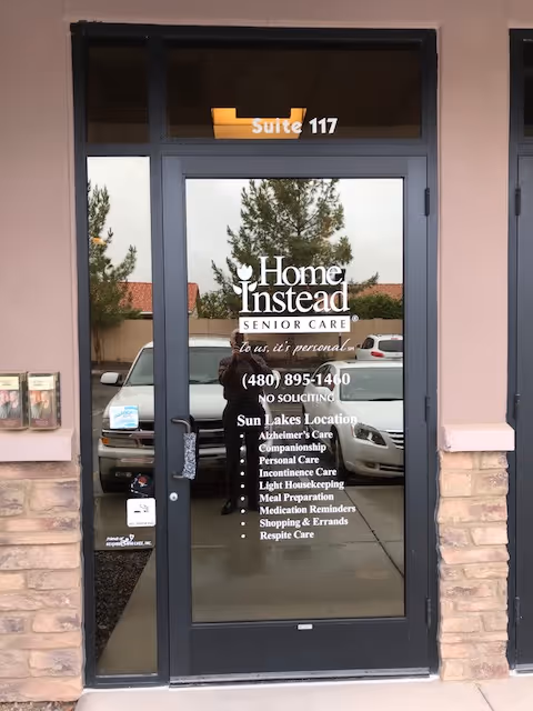 Glass door entrance displaying Home Instead Senior Care logo and contact details.