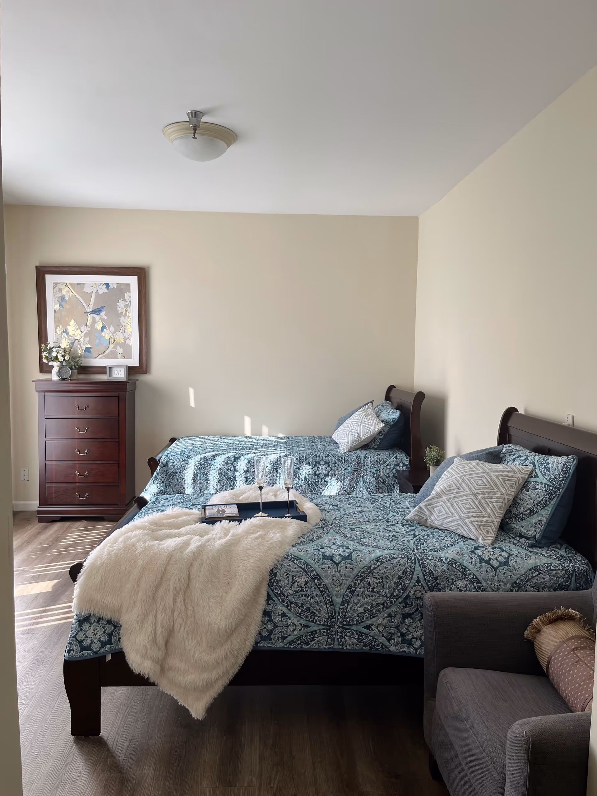 Two twin beds with blue patterned quilts in a tidy beige bedroom.