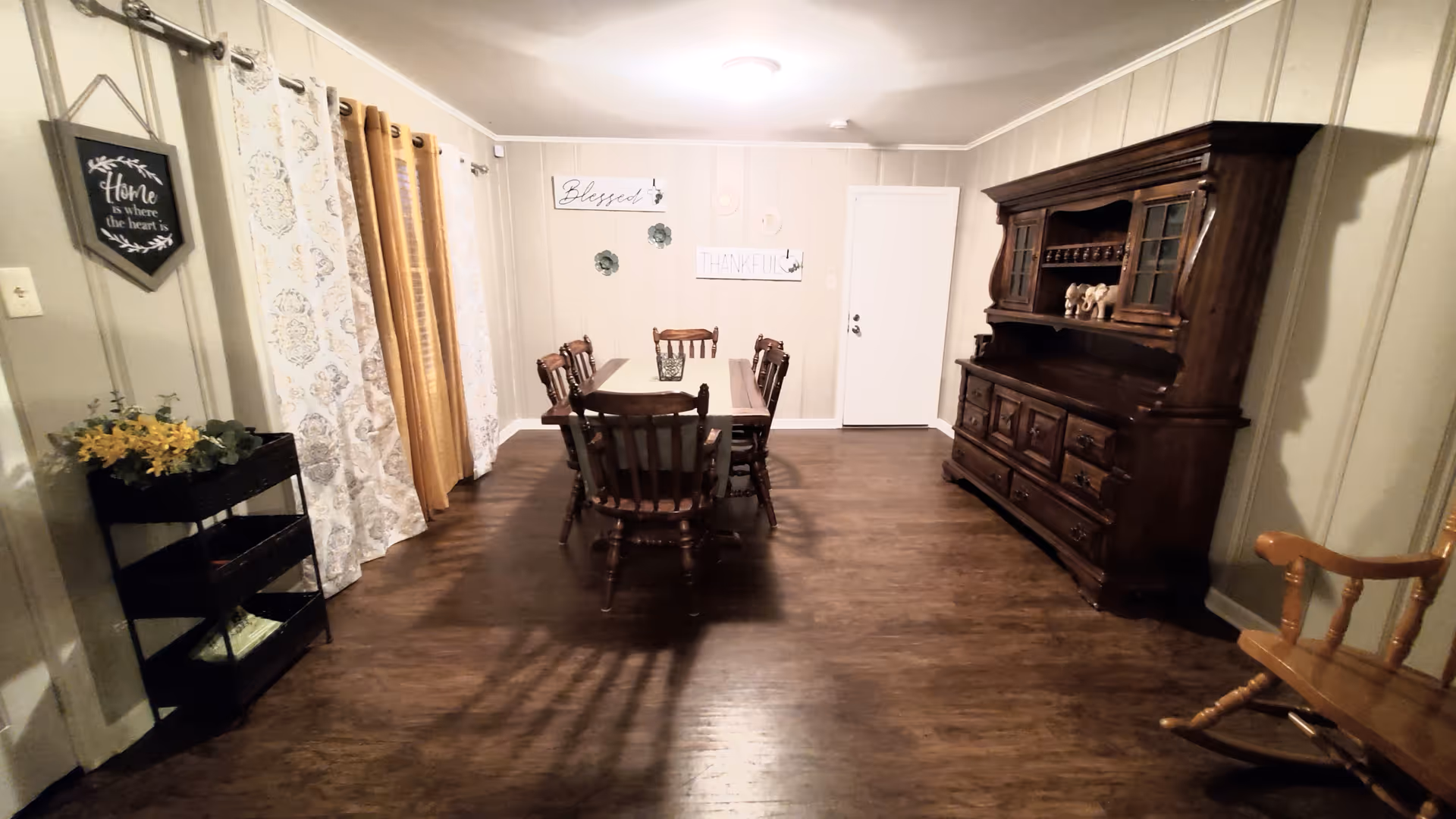 A cozy dining room with a wooden table, chairs, and a large dark hutch.