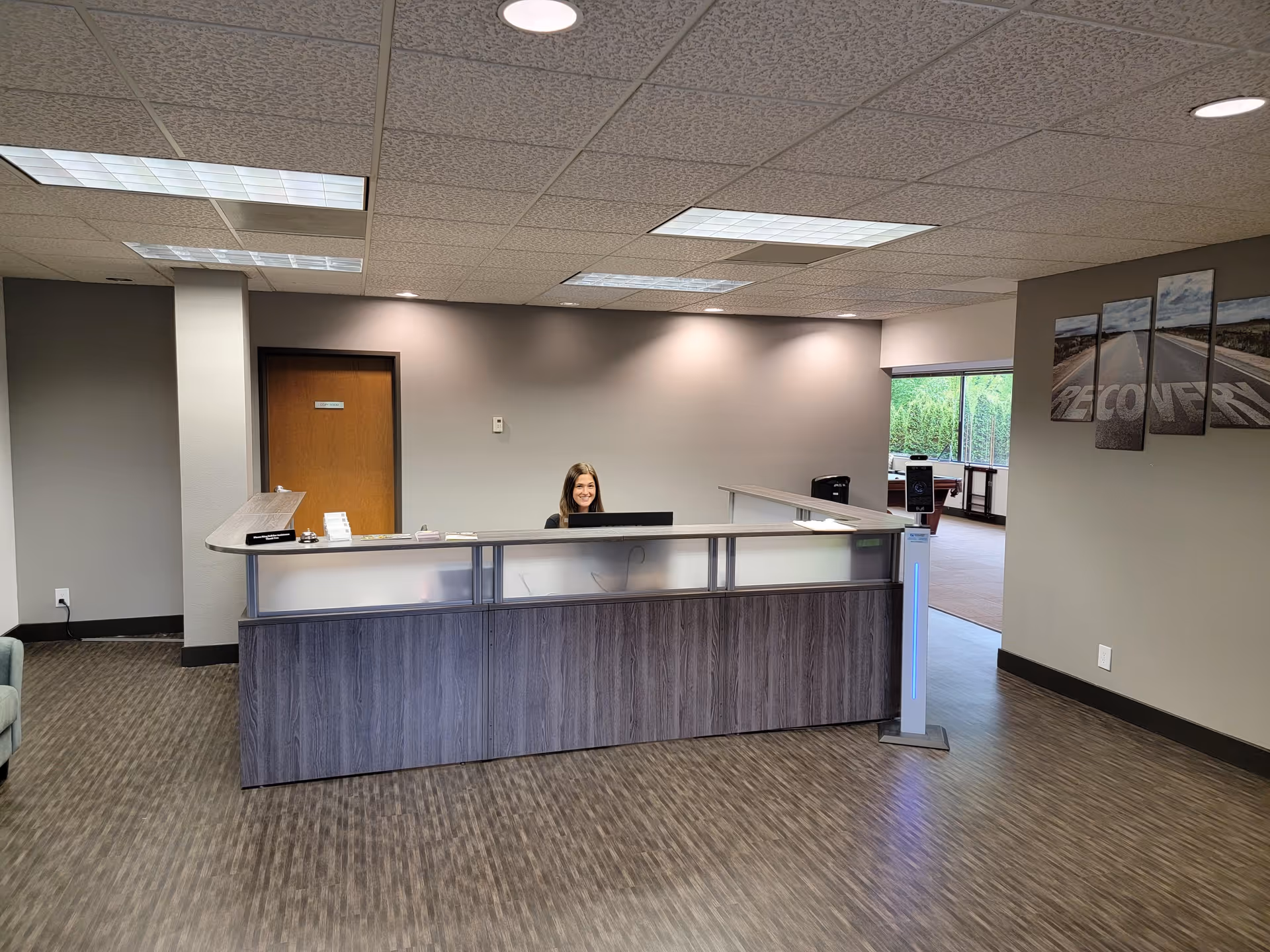 Reception desk with a smiling staff member in a spacious, modern interior lobby.
