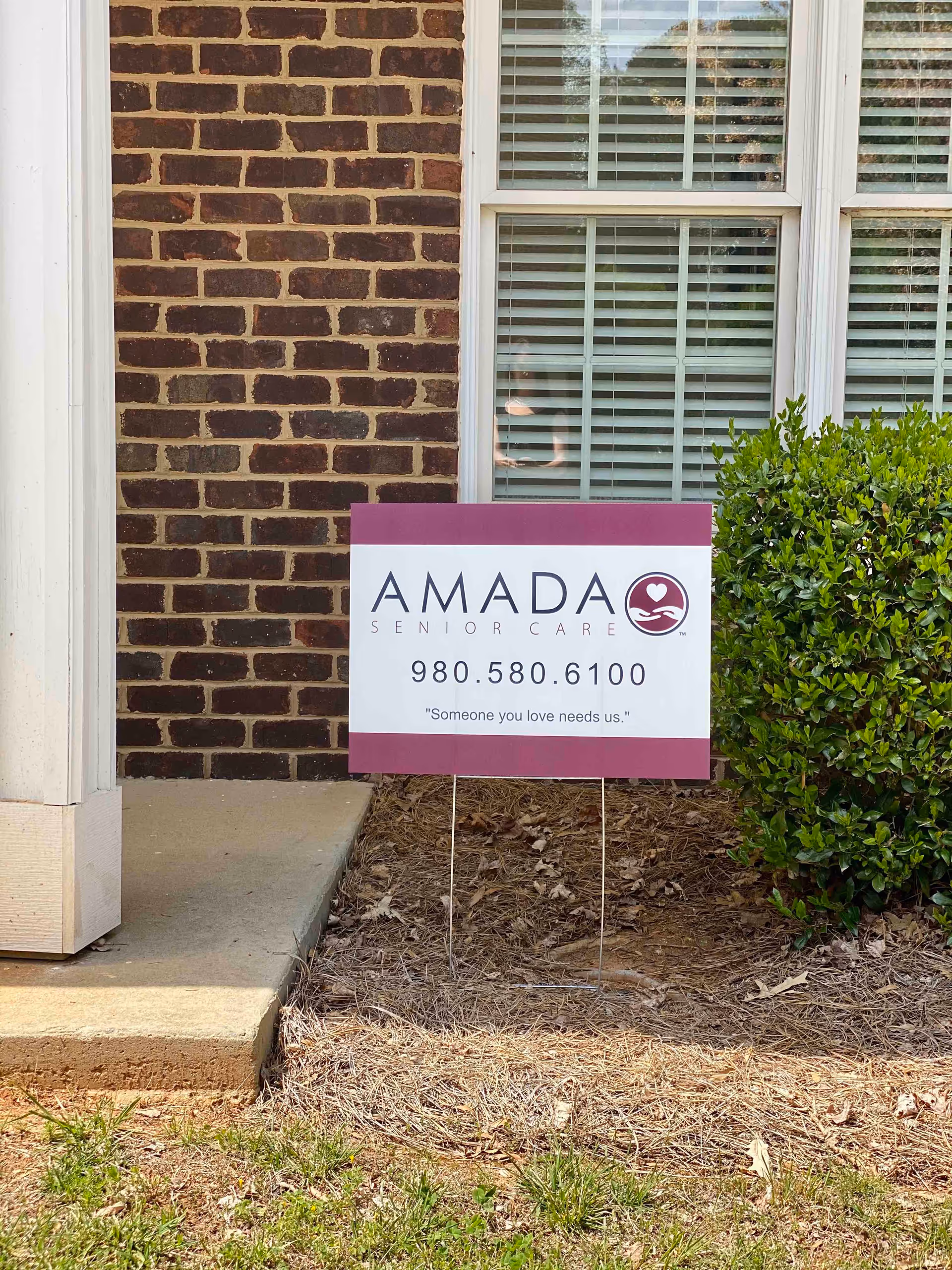 Front exterior of a brick building with an Amada Senior Care sign.