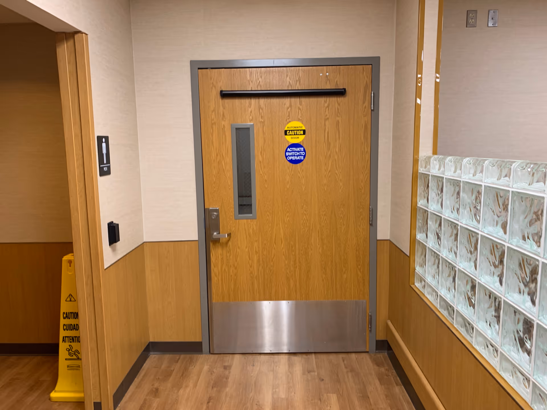 Wooden door with metal kick plate in a hospital hallway.