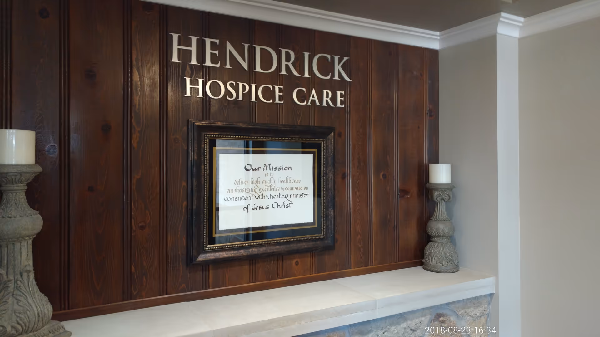 Interior lobby with Hendrick Hospice Care sign, framed certificate, and candle holders.