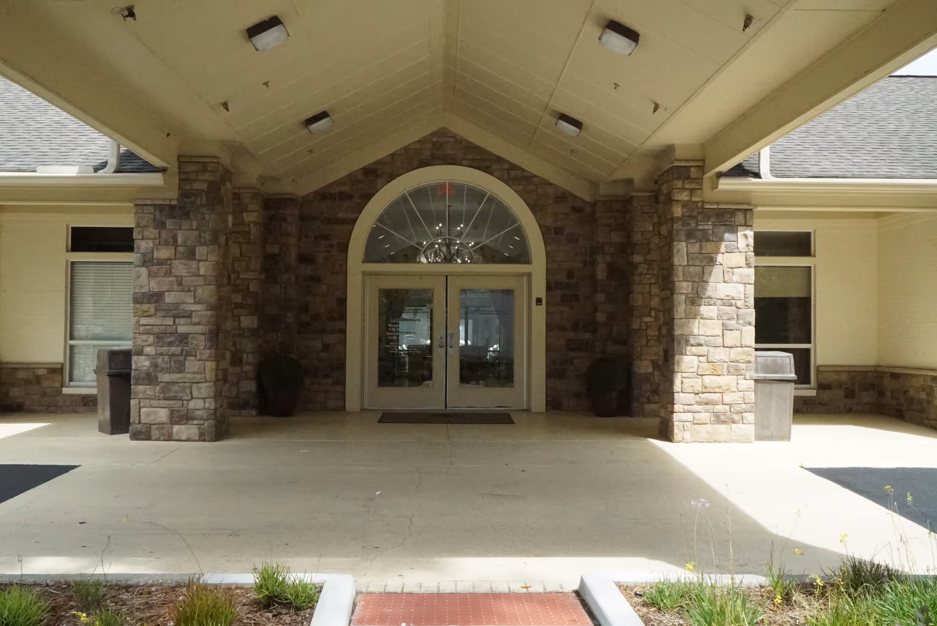 Front entrance of a senior living facility with stone pillars and glass doors.