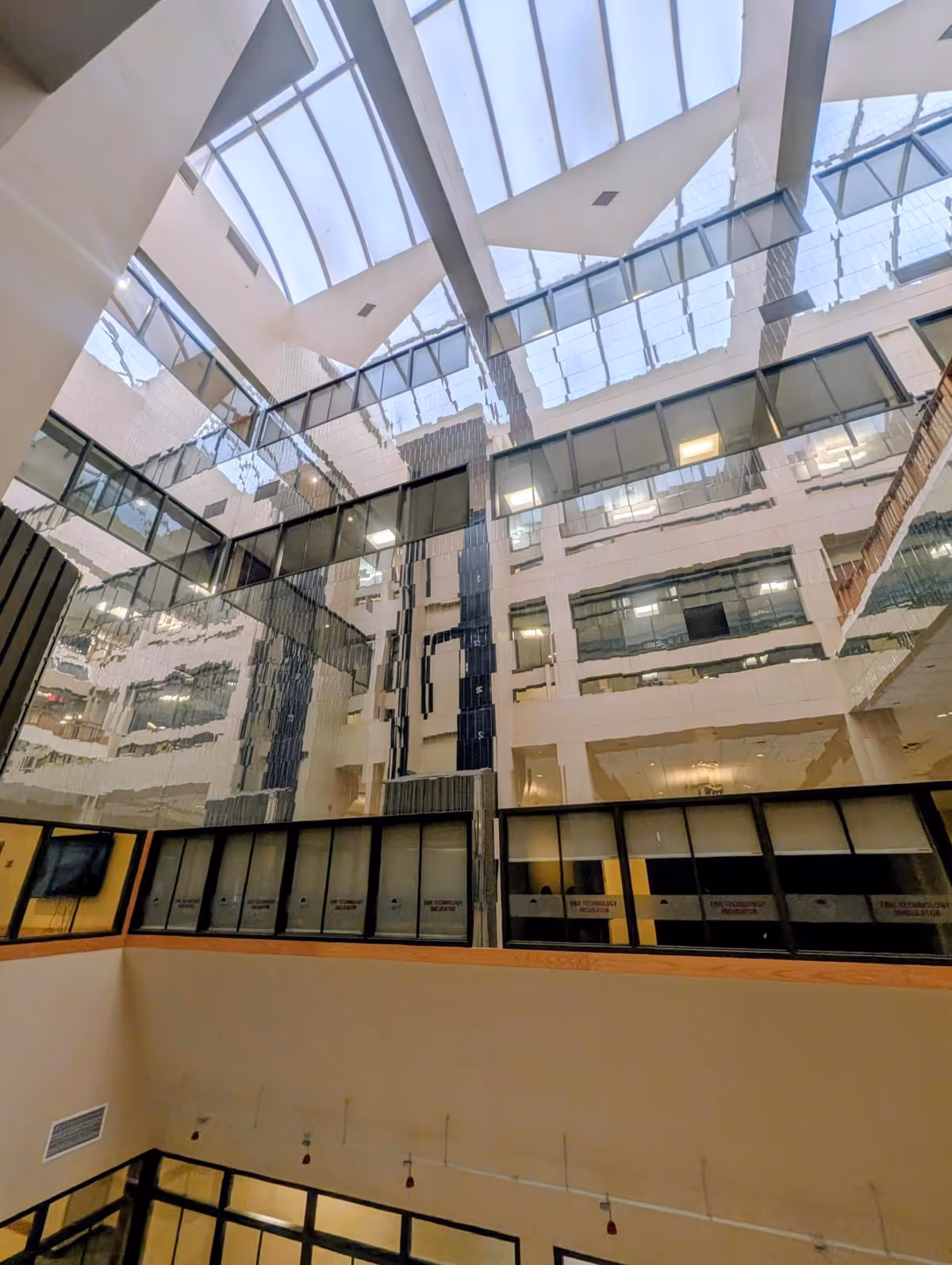 Open atrium interior with glass balconies and skylights spanning multiple floors in a modern facility today.