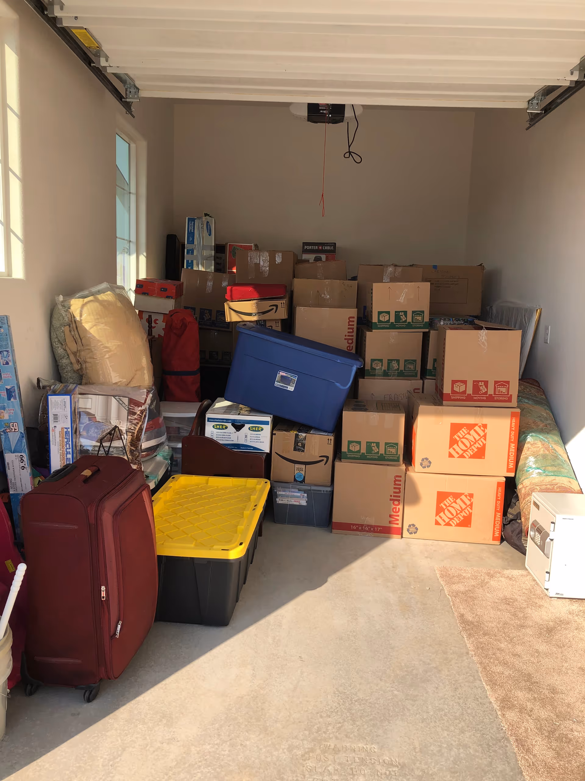 Cluttered storage room filled with stacked boxes, suitcases, and plastic bins.