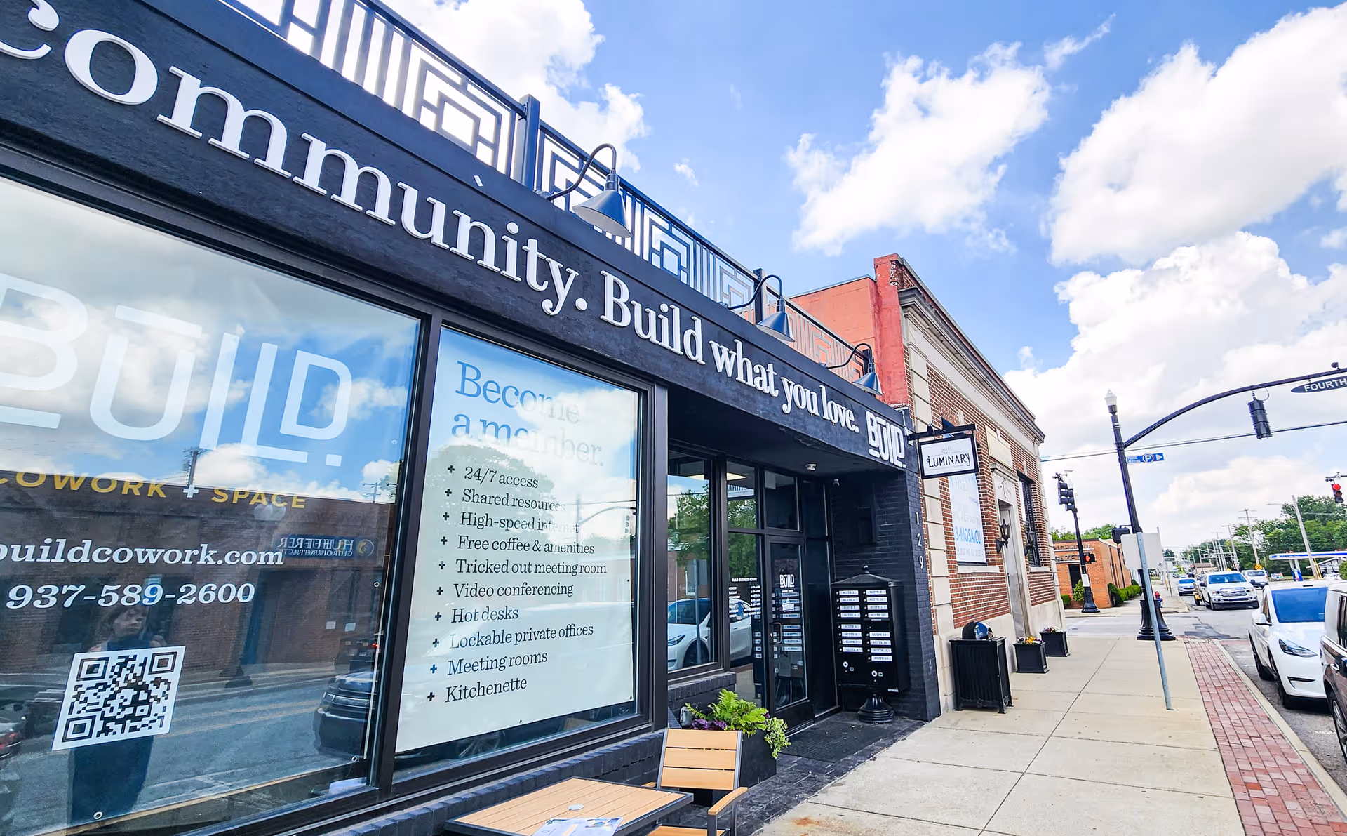 Exterior street view of a storefront with large windows and blue sky.