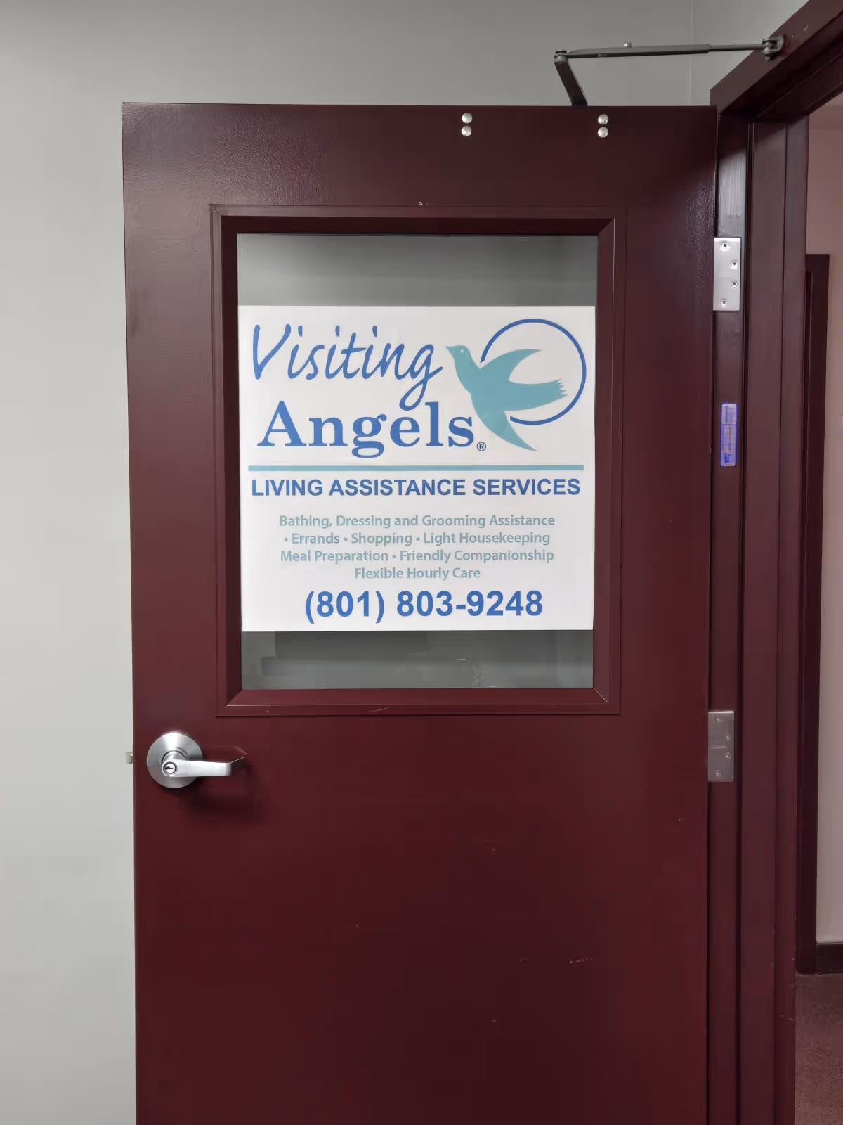 Maroon interior door with a windowed sign for Visiting Angels Living Assistance Services.