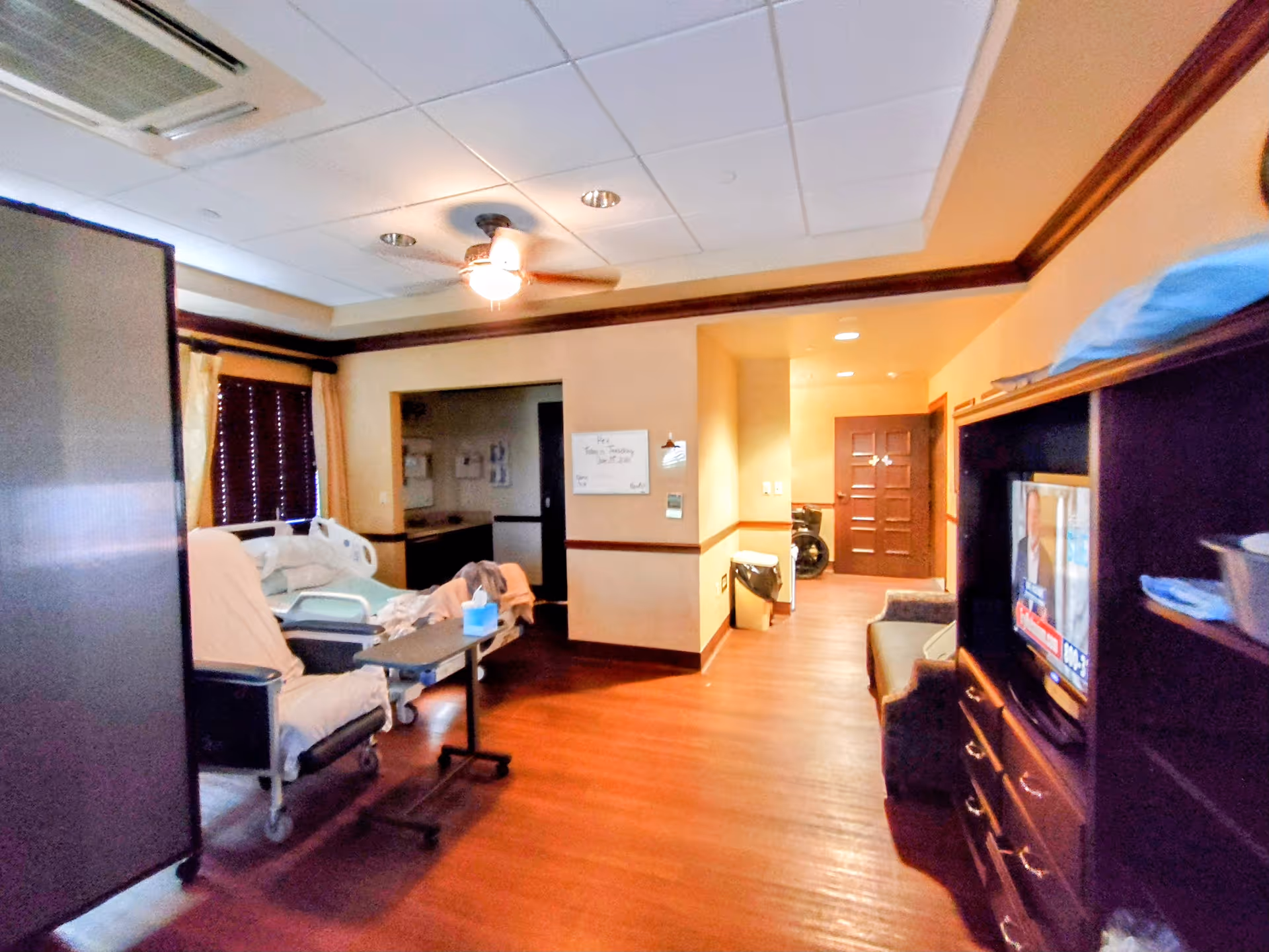 Interior of Gulfside Healthcare Services facility featuring a patient bed, seating area, and TV.