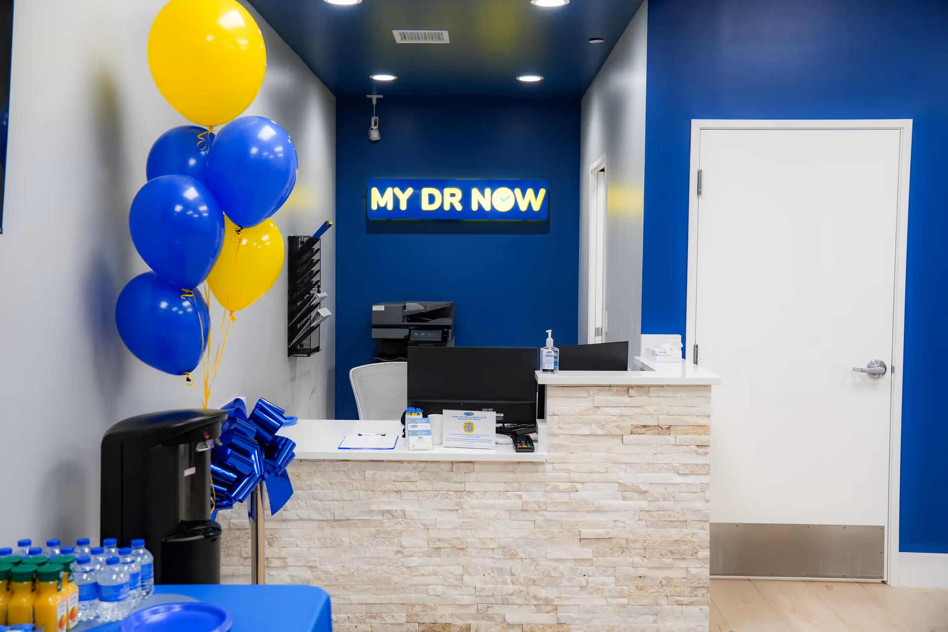 Reception desk inside a MY DR NOW facility with blue walls and balloons.