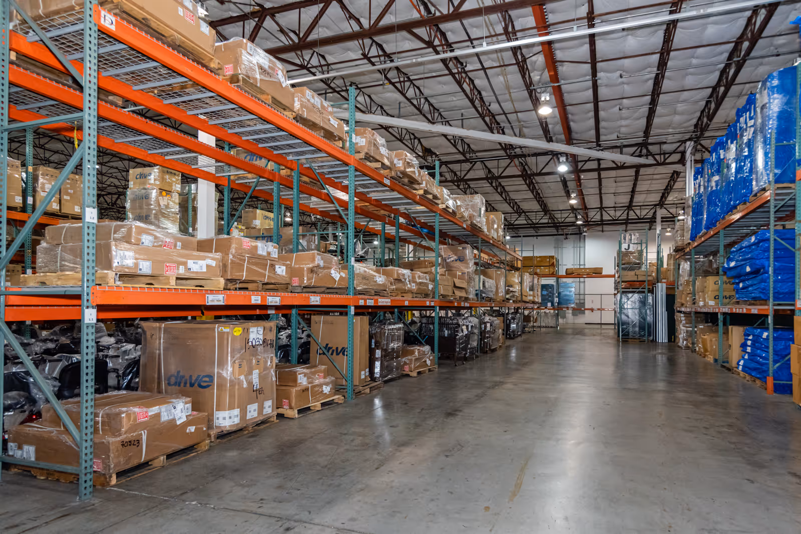 Industrial warehouse interior with tall steel shelves loaded with boxed pallets.