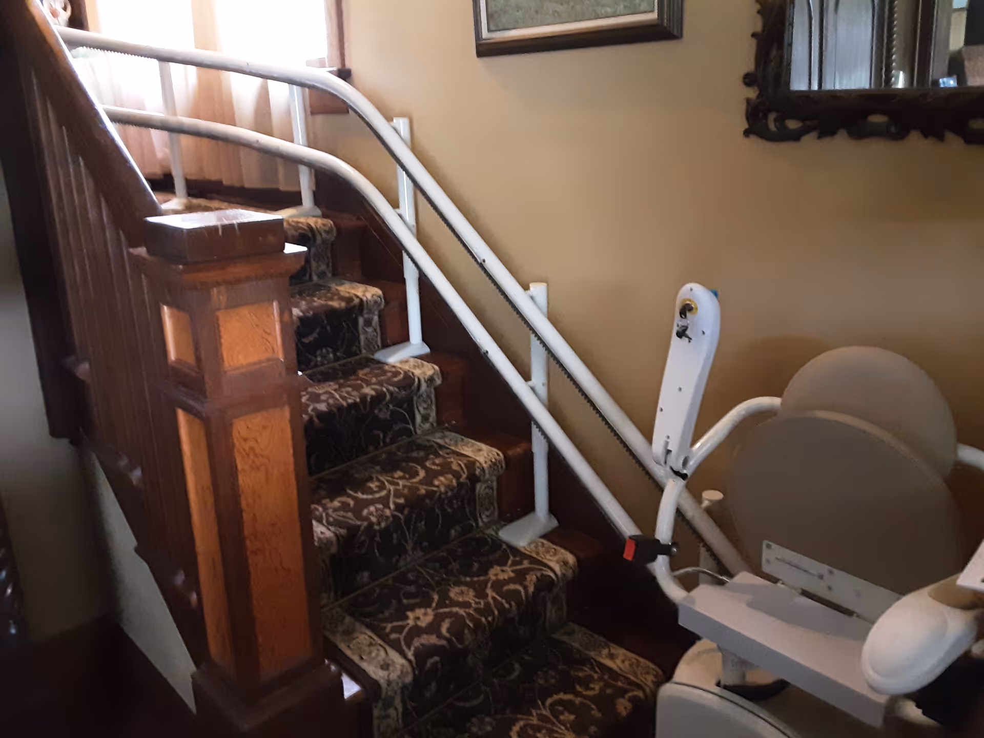Indoor staircase with patterned carpet and a stairlift rail along the wall.