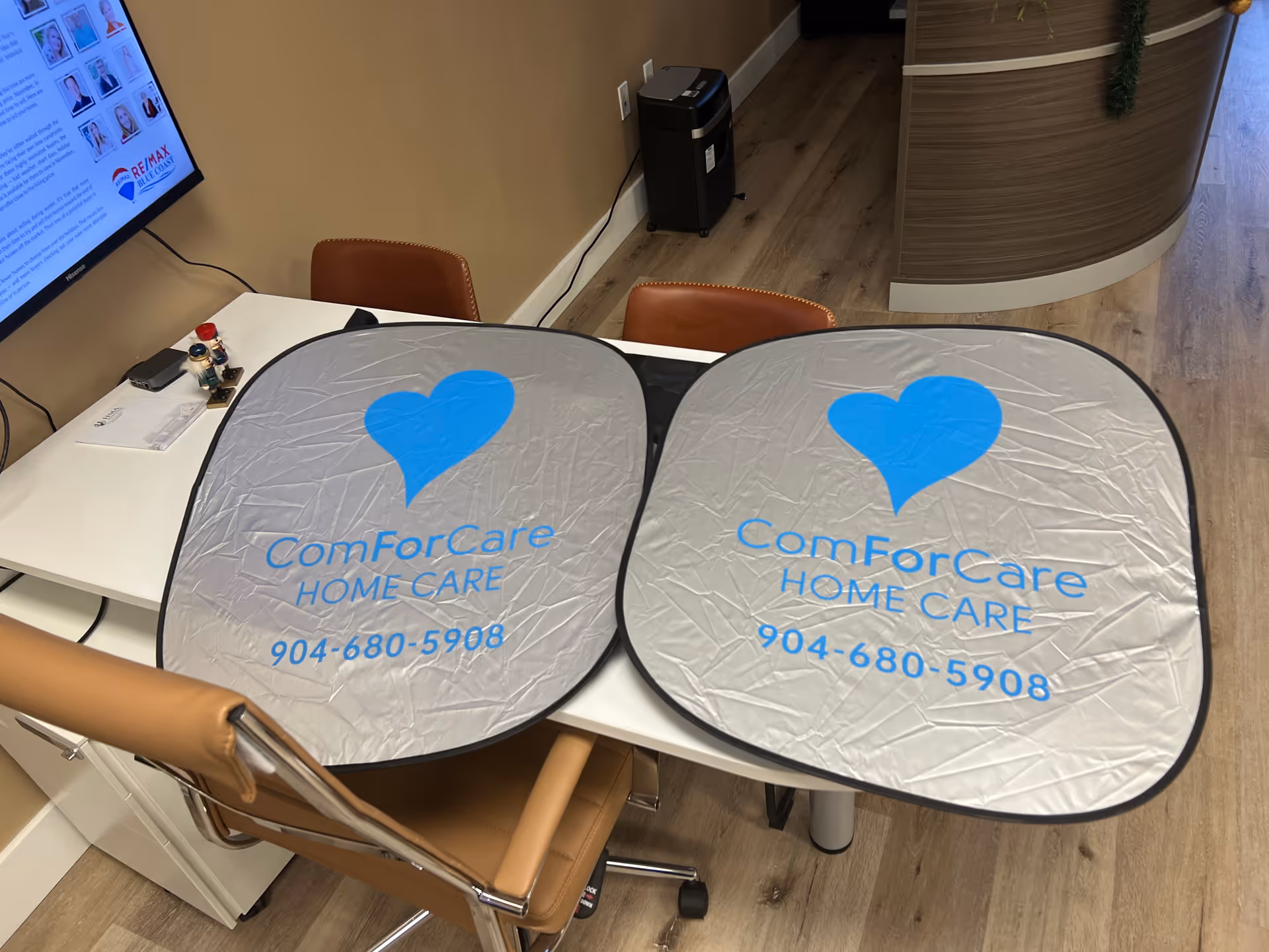 Indoor reception area featuring two ComForCare Home Care promotional logo signs on the desk.