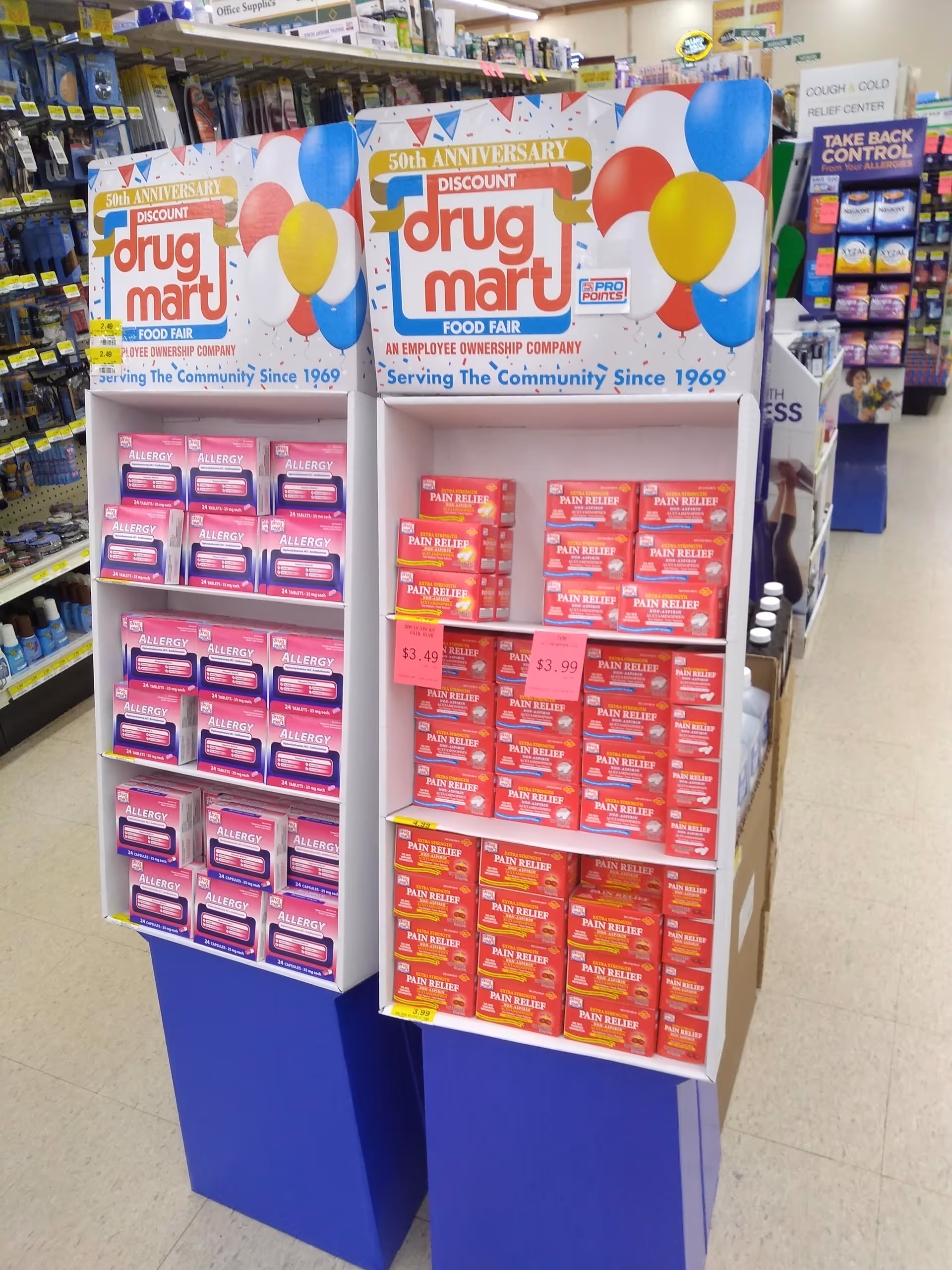 Colorful drug display units with Discount Drug Mart branding in a bright store aisle.