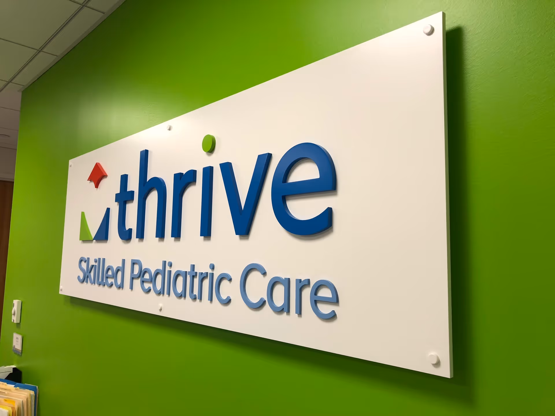 Interior wall with bright green paint and a Thrive Skilled Pediatric Care sign.