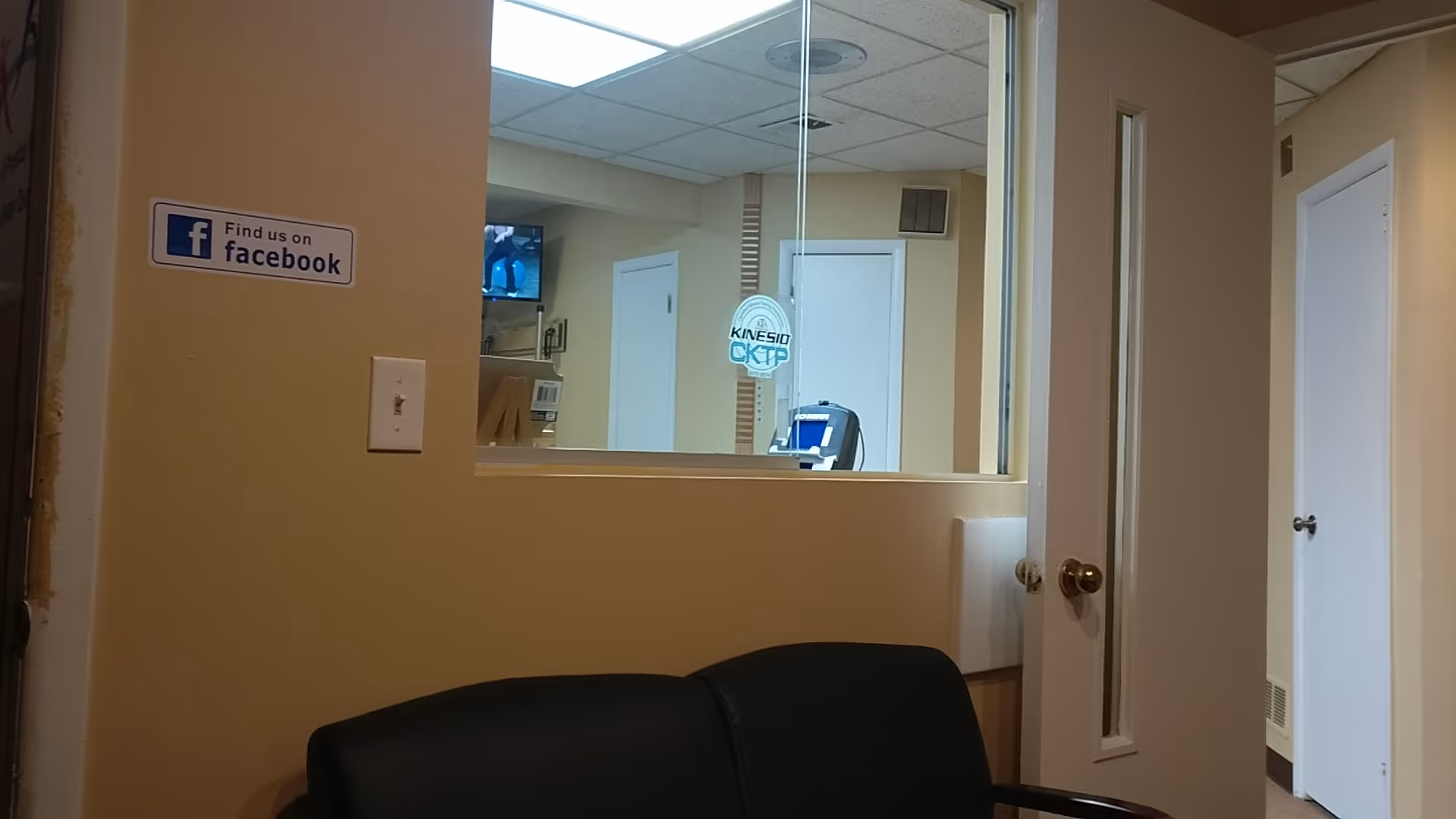 Interior view of a rehab clinic with a window, beige walls, and a black couch.