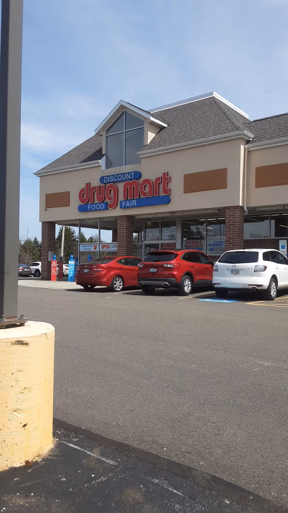 Front view of Discount Drug Mart storefront with several parked cars in the lot.